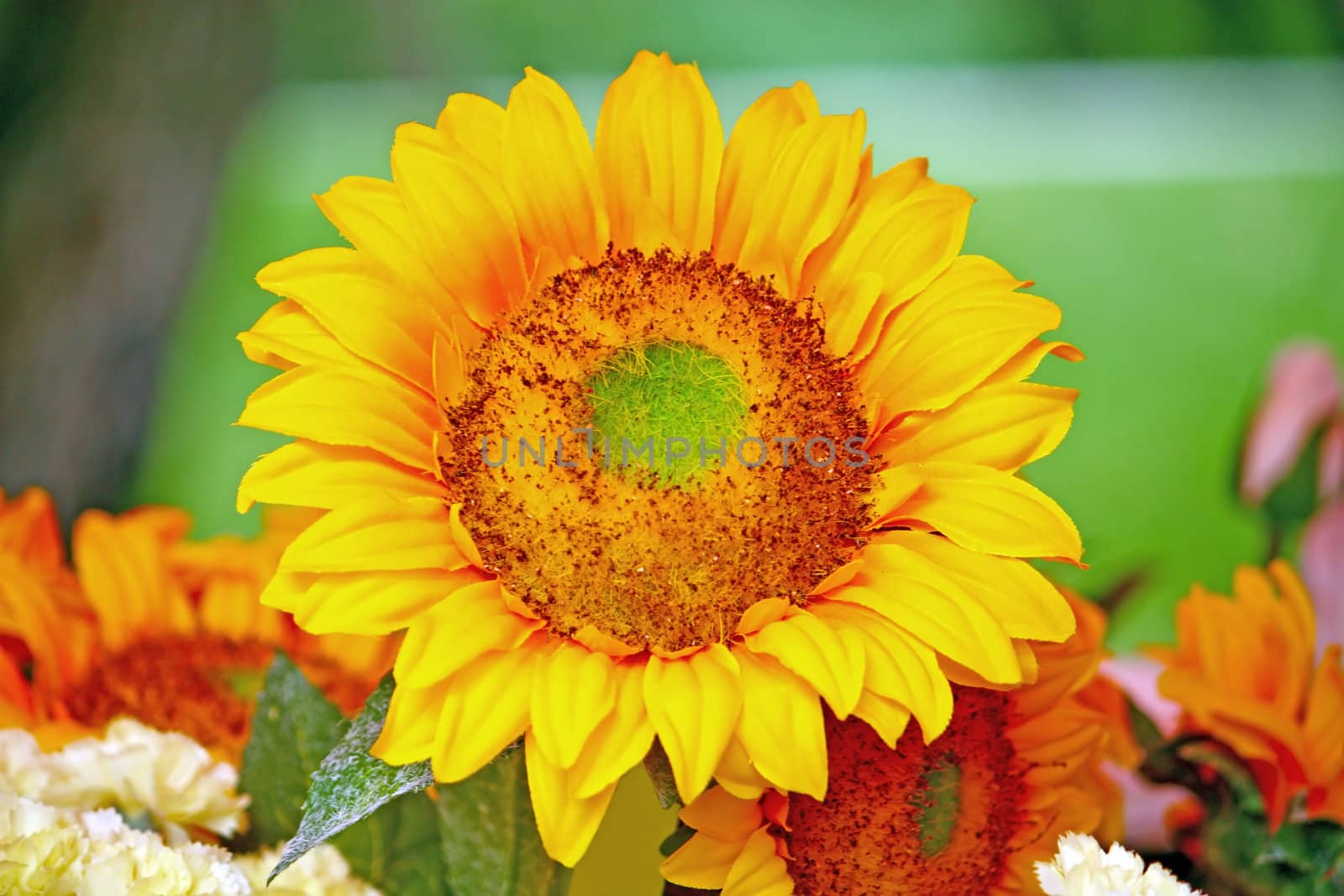 Artificial sunflower in the front of other flowers