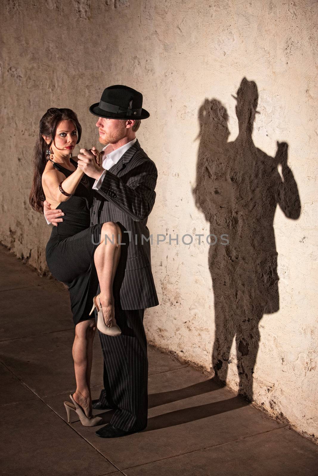 Beautiful female tango dancer with leg up next to partner