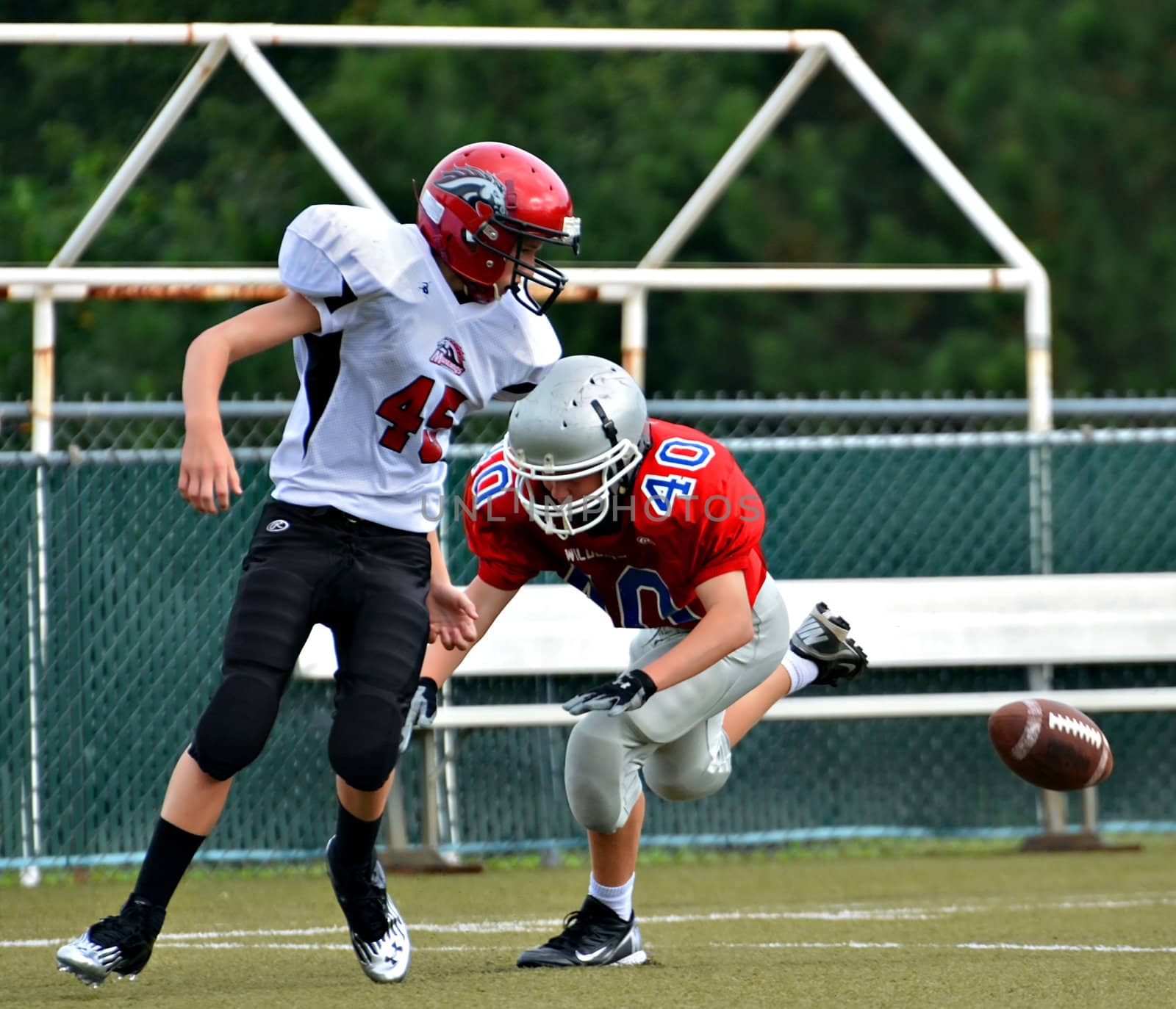 CUMMING, GA/USA - SEPTEMBER 8: Andy Leggett making a tackle on an unidentified opponent during a football game. Two teams of 7th grade boys September 8, 2012 in Cumming GA. The Wildcats  vs The Mustangs.