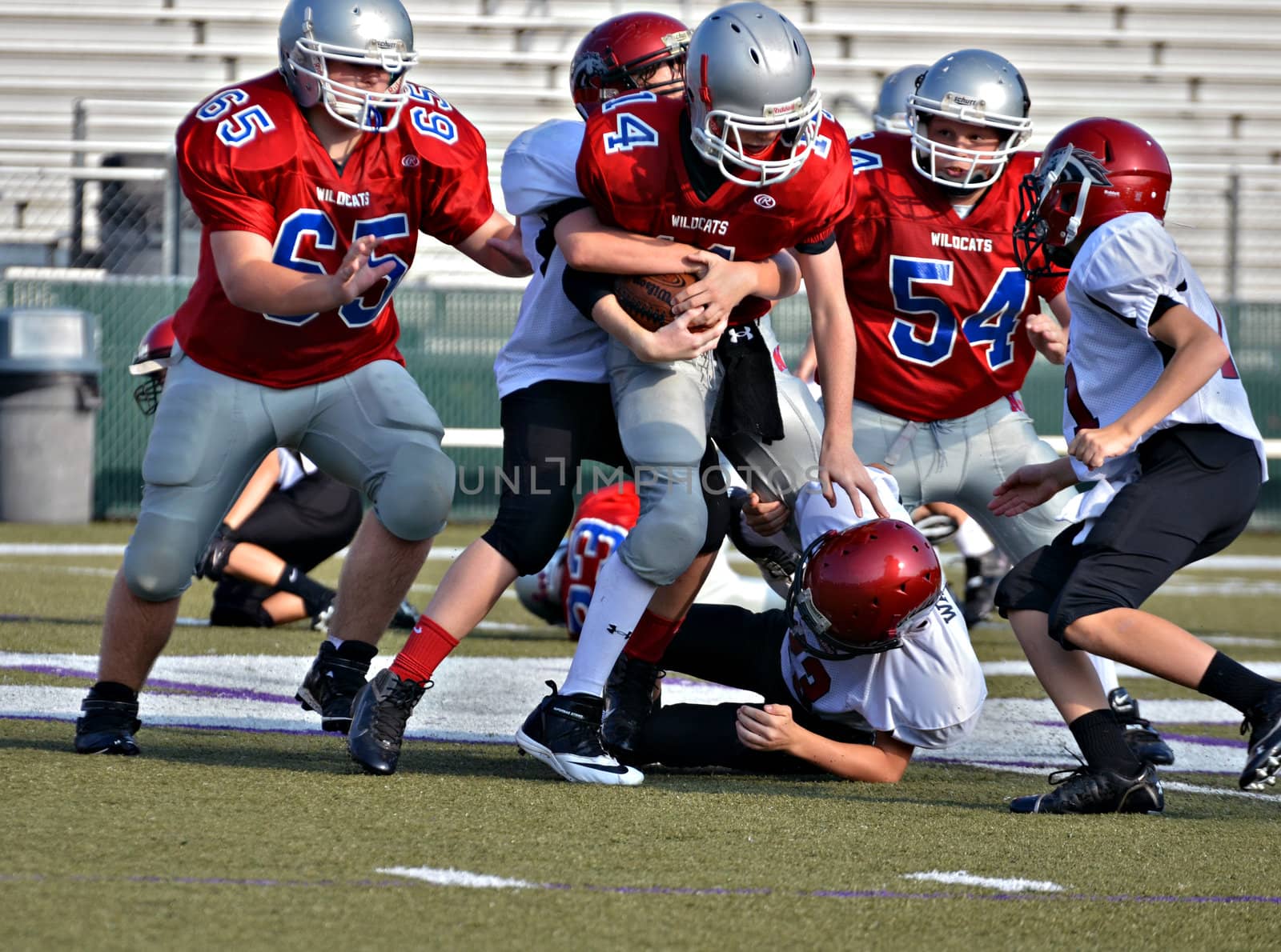 CUMMING, GA/USA - SEPTEMBER 8: Unidentified boys blocking and tackling during a football game. Two teams of 7th grade boys September 8, 2012 in Cumming GA. The Wildcats  vs The Mustangs.