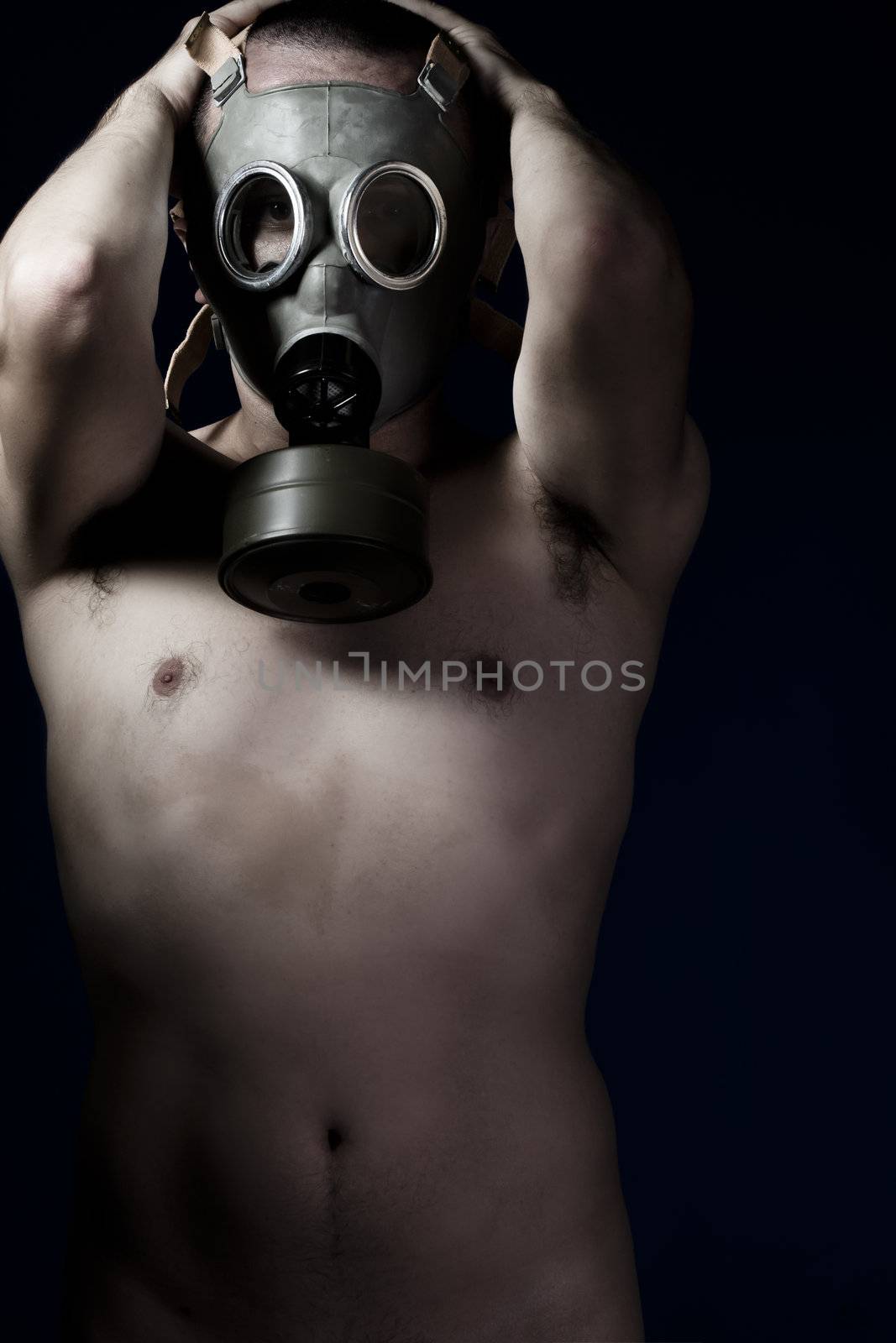 Naked man with hands on his head and gas mask