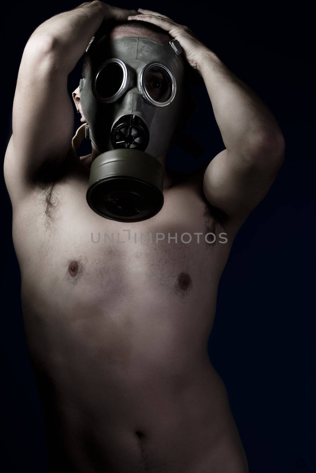 Naked man with hands on his head and gas mask
