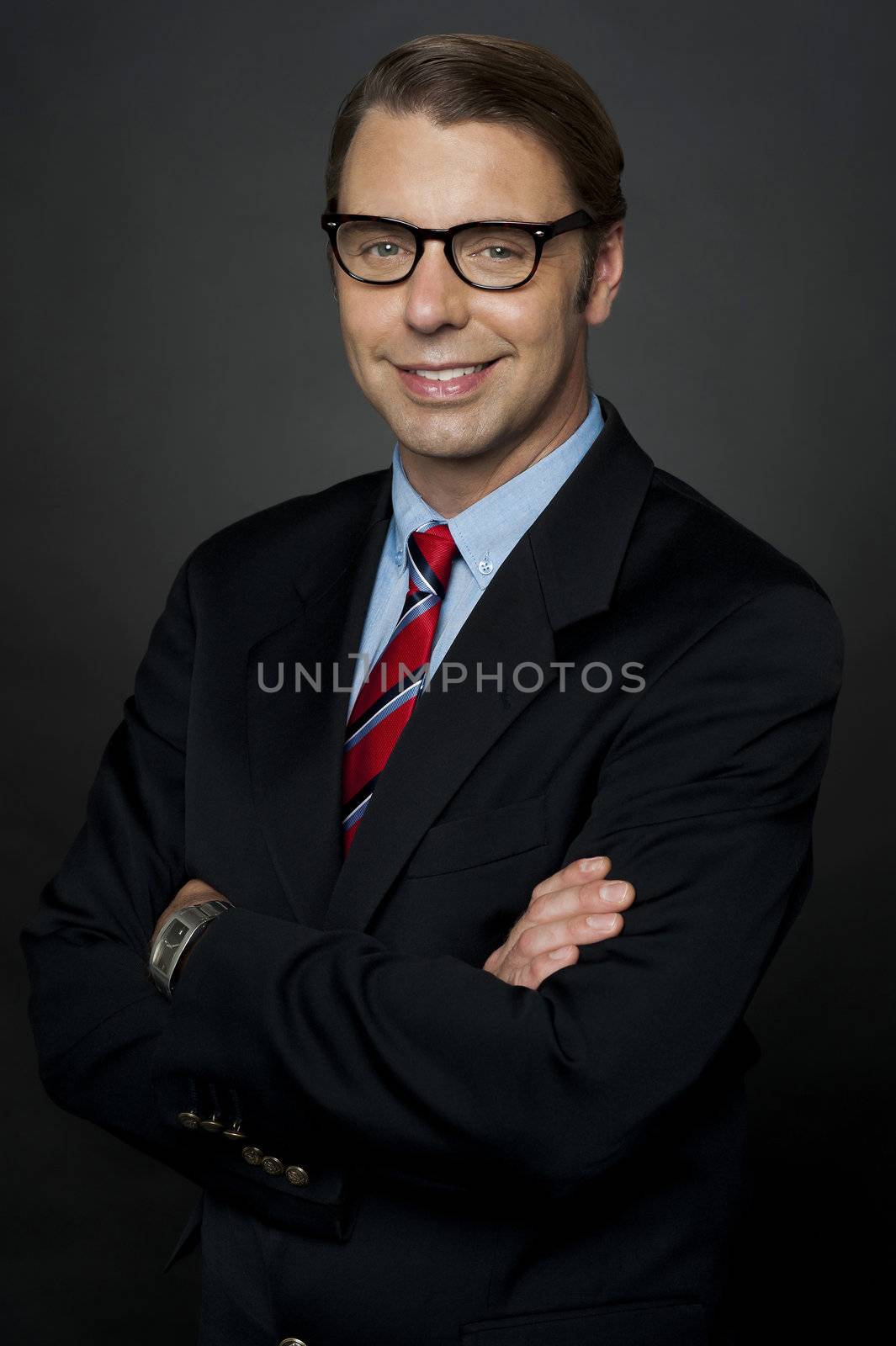 Confident young manager posing with folded arms over black background
