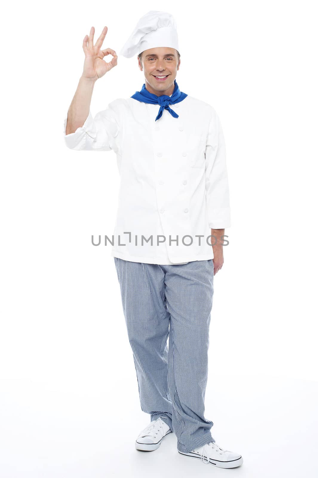 Full length portrait of chef showing okay sign to camera isolated over white