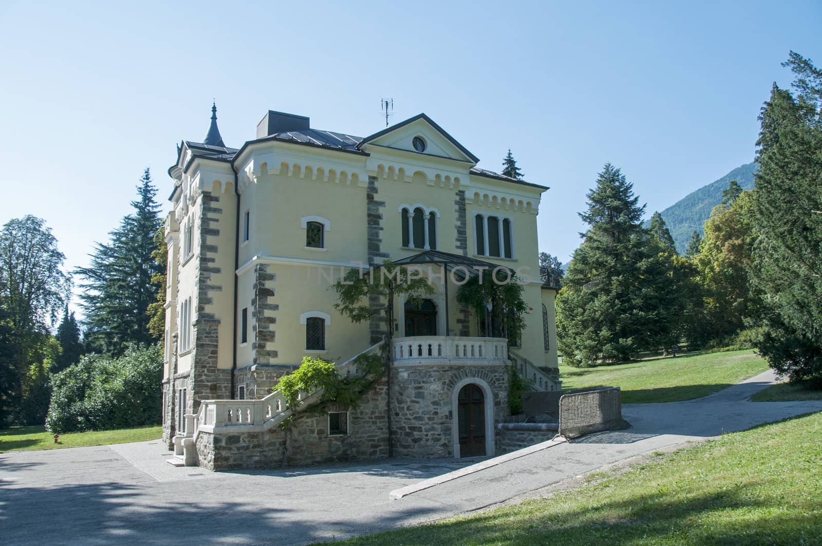 big building in Italy in the place Levico Terme with green trees and grass around