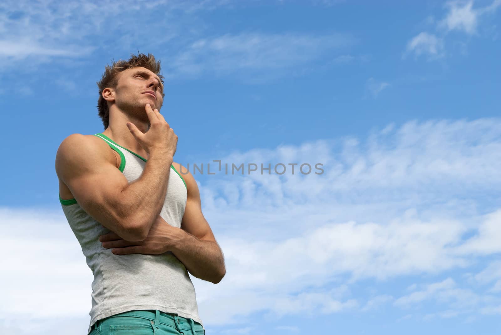 Portrait of a thoughtful strong man, on blue sky background.