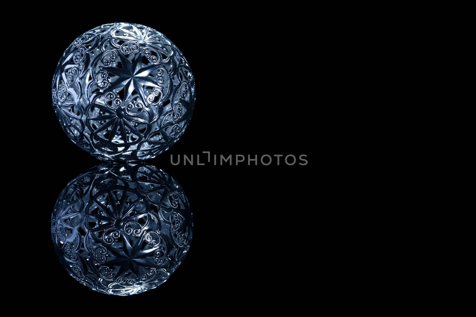 blue metal christmas ball on a black mirror on black background