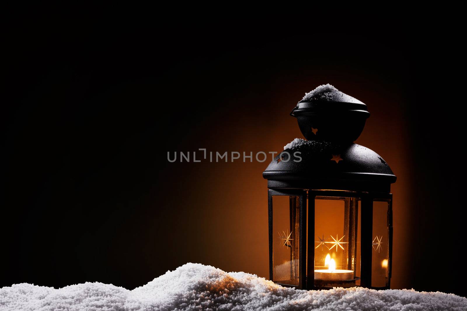 burning black vintage christmas lantern in the night on snow