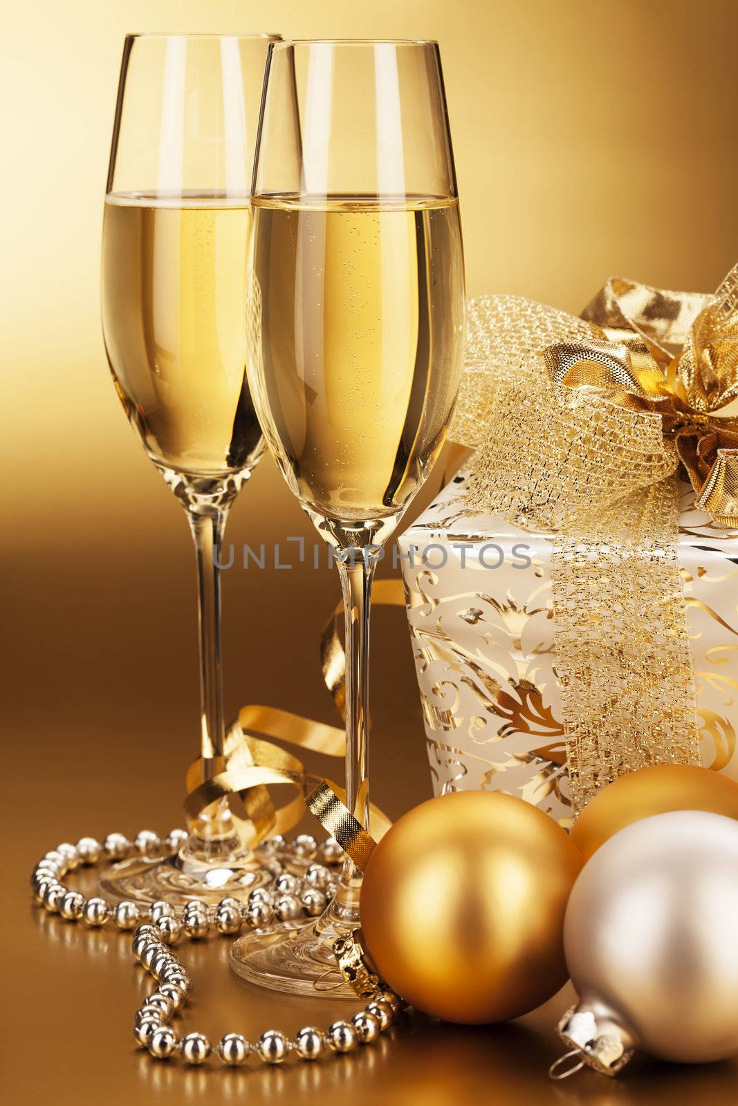 two glasses of champagne with christmas balls and a christmas present