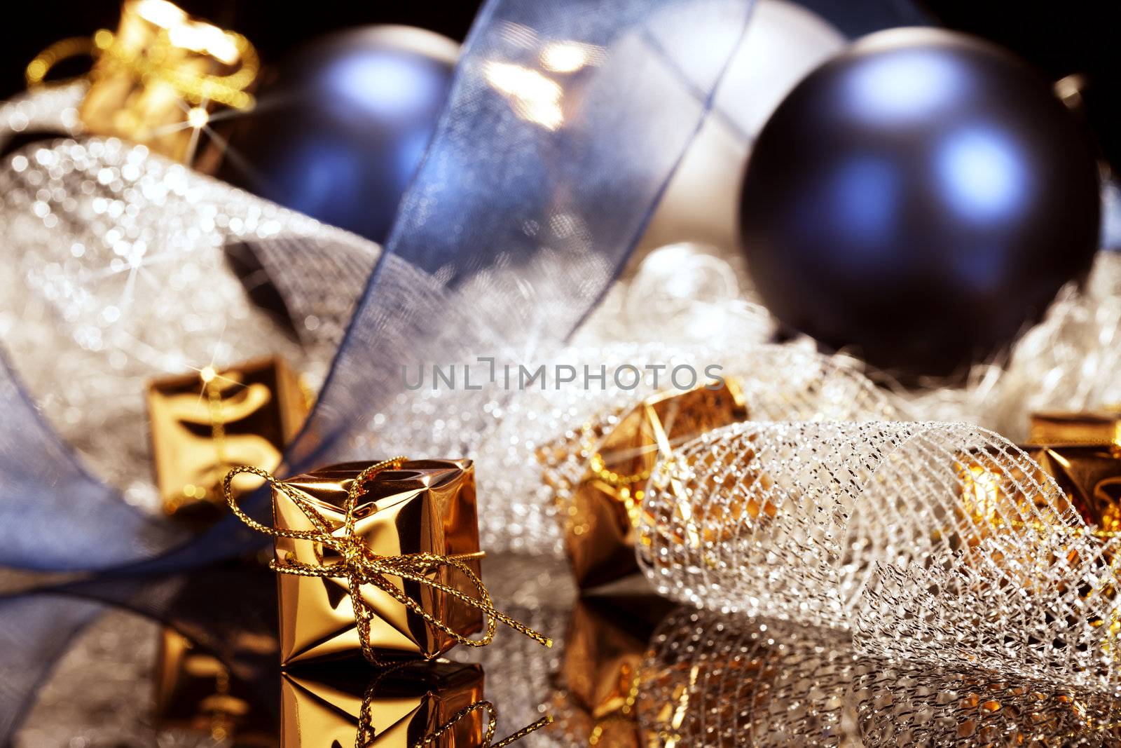 tiny shiny golden christmas present in front of christmas decoration with christmas balls and ribbons