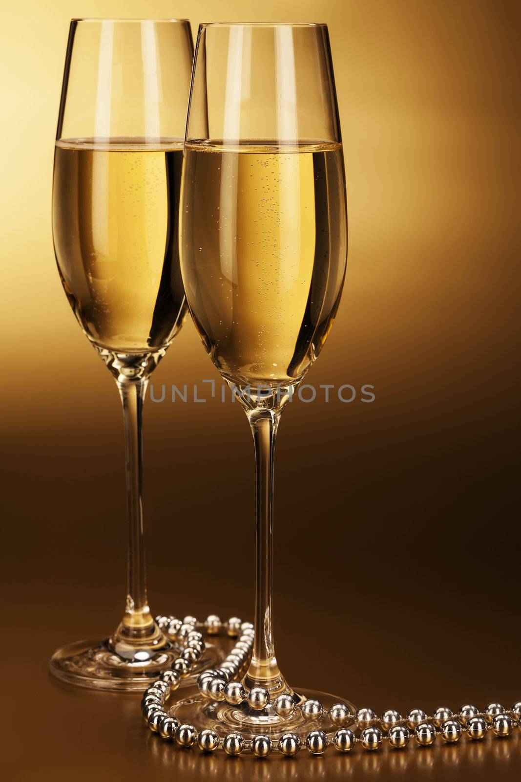 two glasses of champagne with a silver chain on golden background