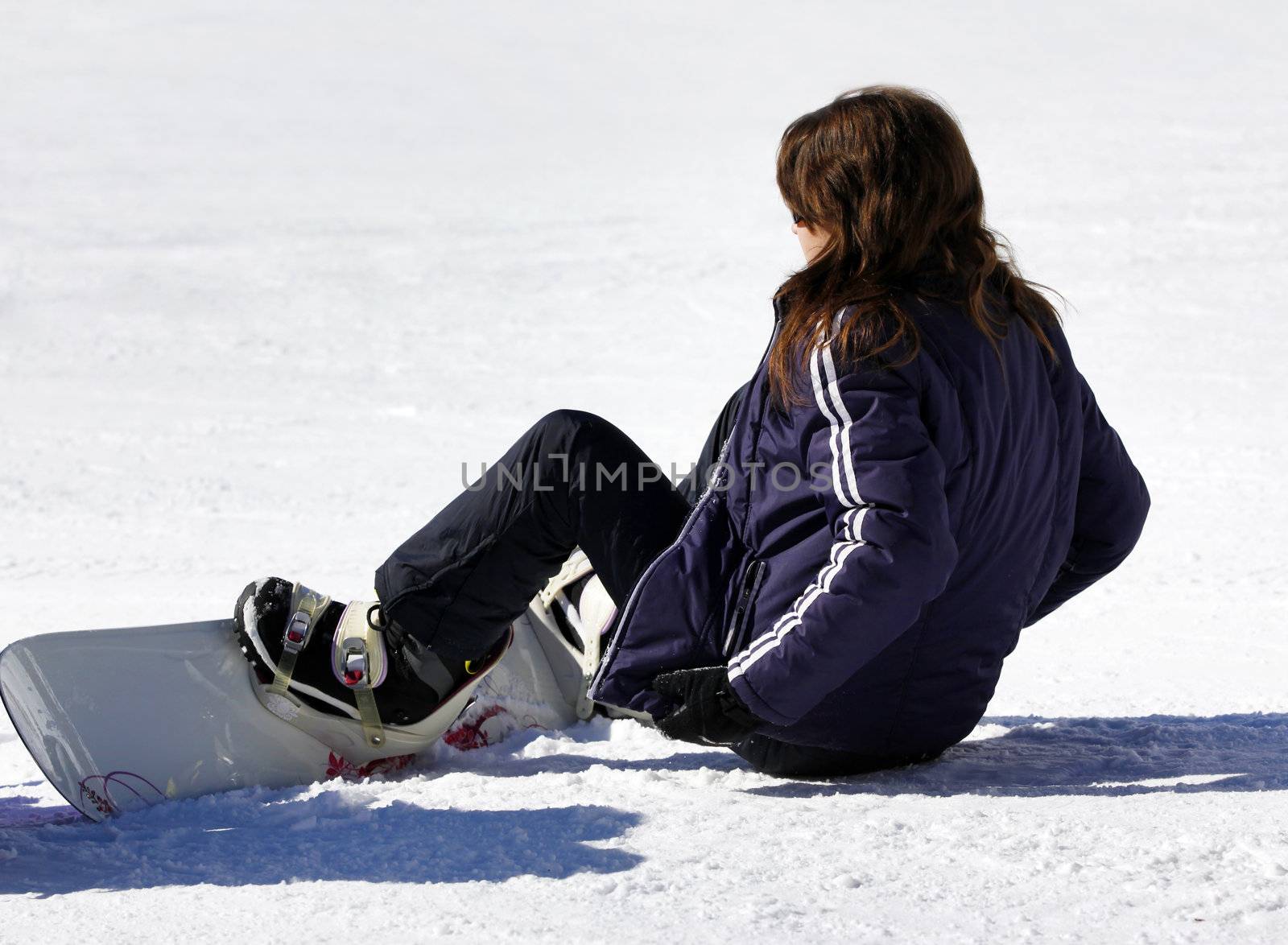 Young woman with snowboard sitting in the snow