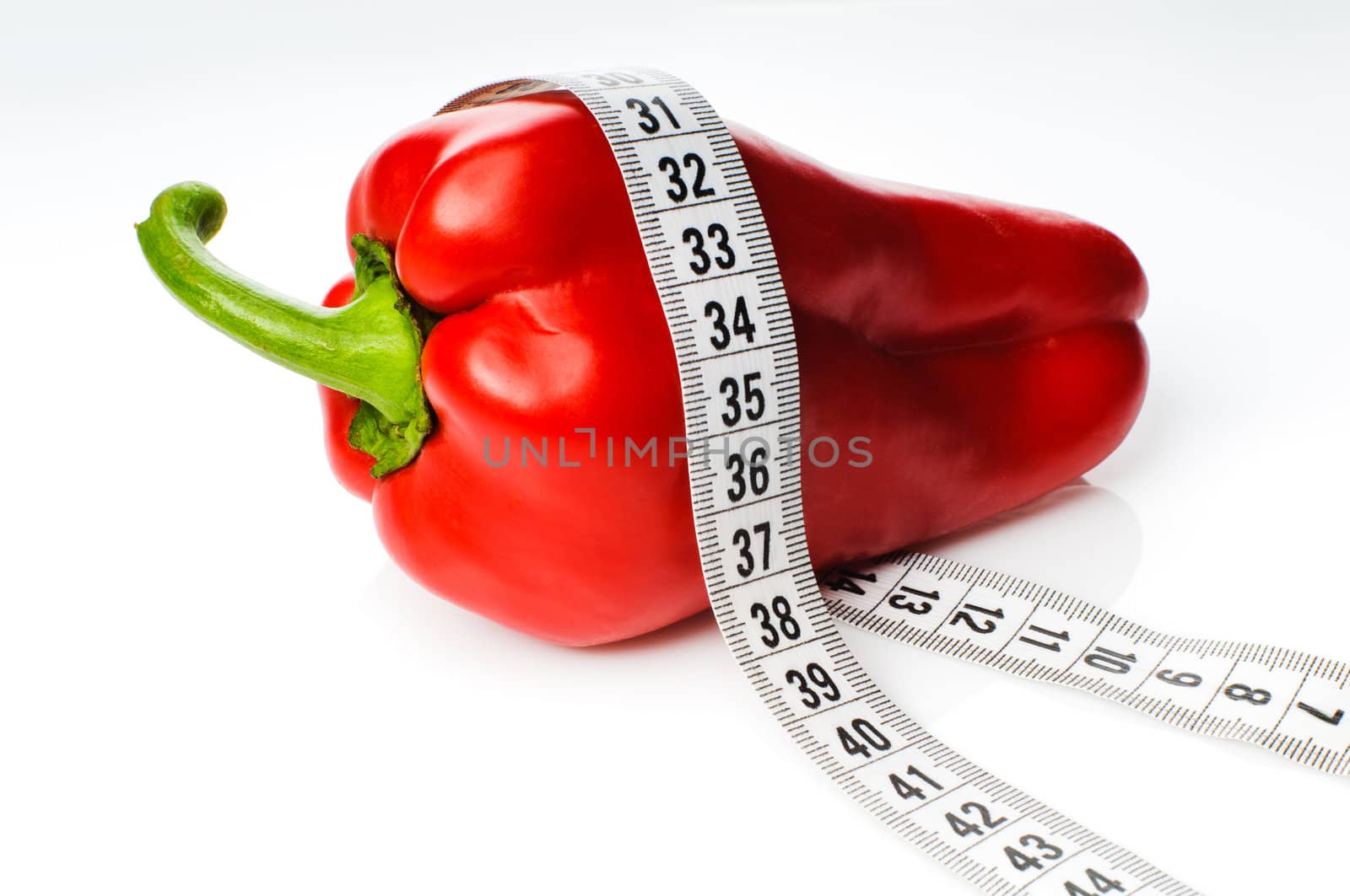 Red sweet pepper in measure tape isolated on white background