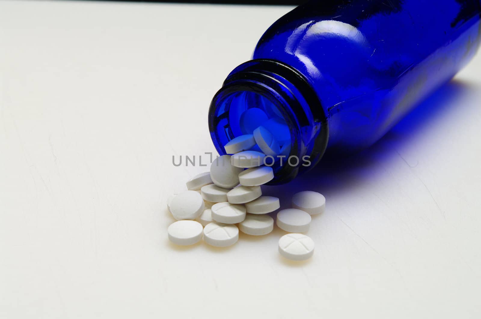 Spilled pills from a  blue bottle