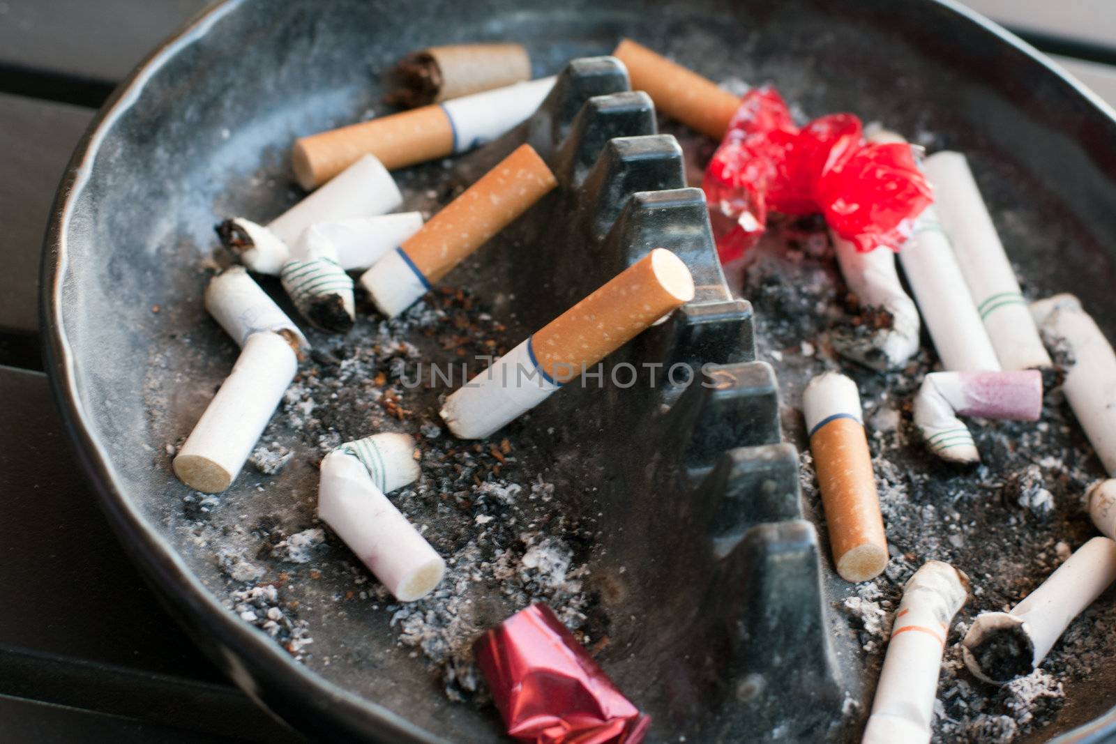ashtray full with buts and lipstick and paper