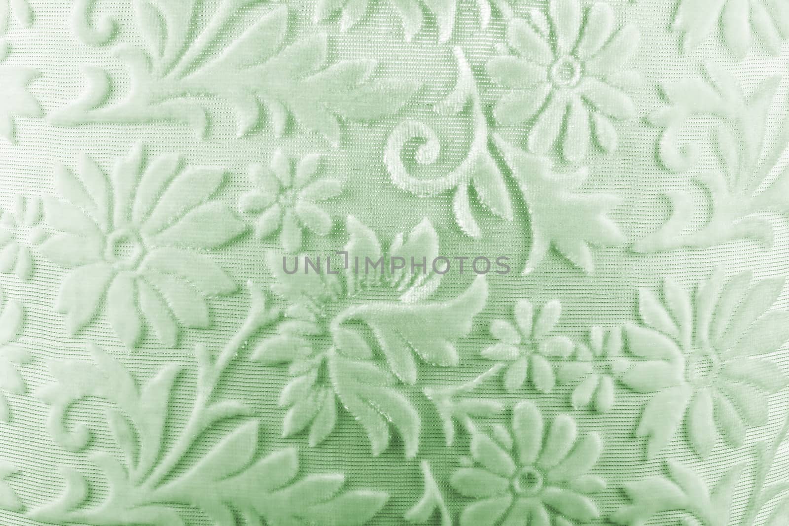 A background of a soft light green colored fabric with floral pattern.