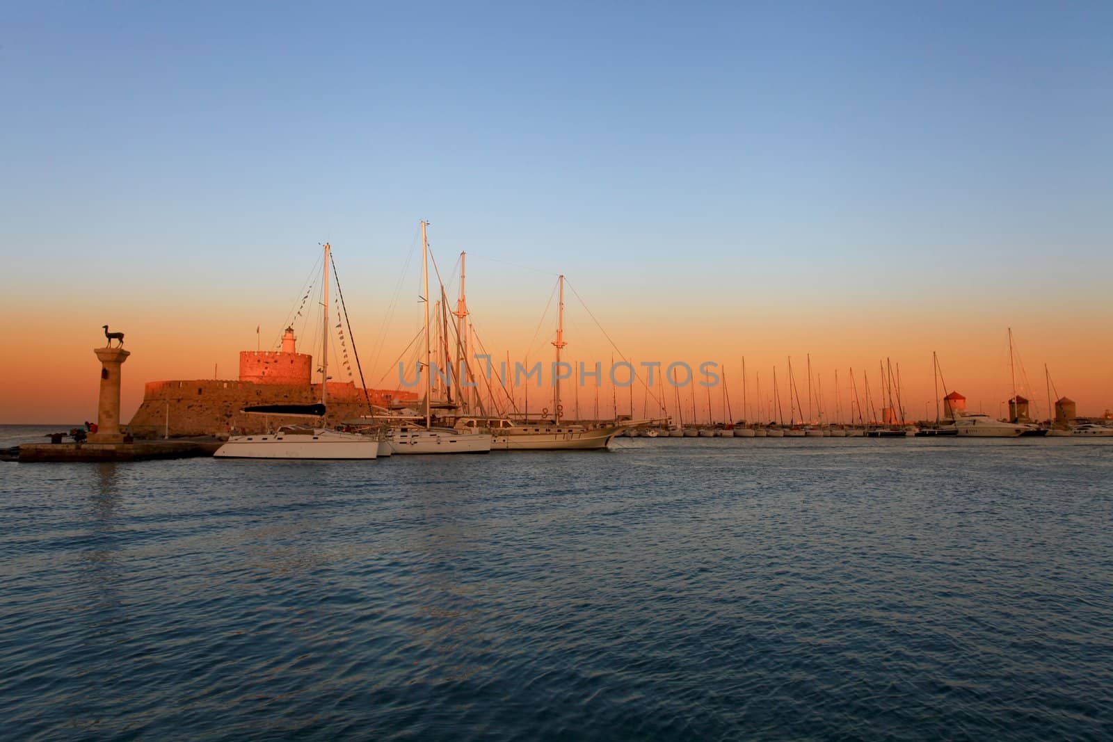 Rhodes harbor and windmills in Greece at sunset by olliemt