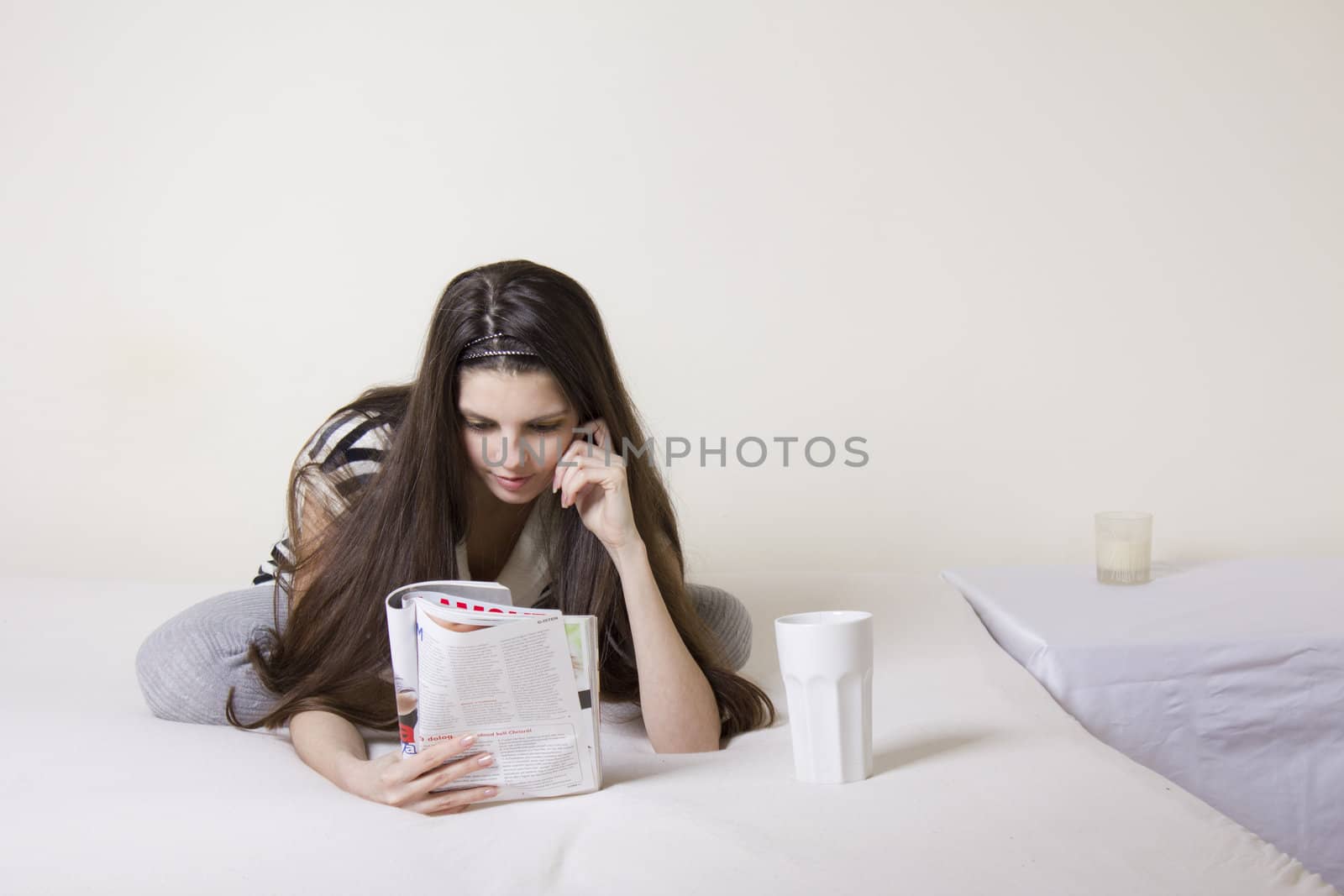 Young woman in bed rearding a fashion magazine