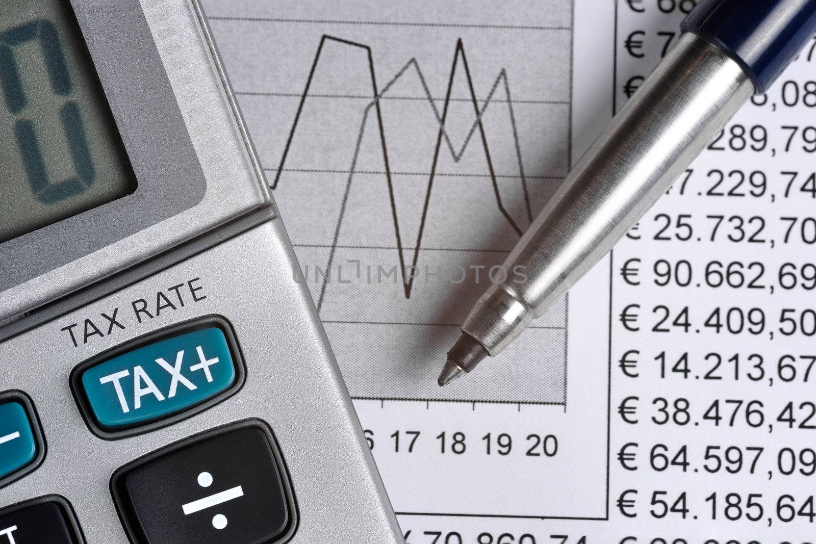 Detail of calculator, focusing the TAX key, next to a sheet of paper with numbers and a metal pen