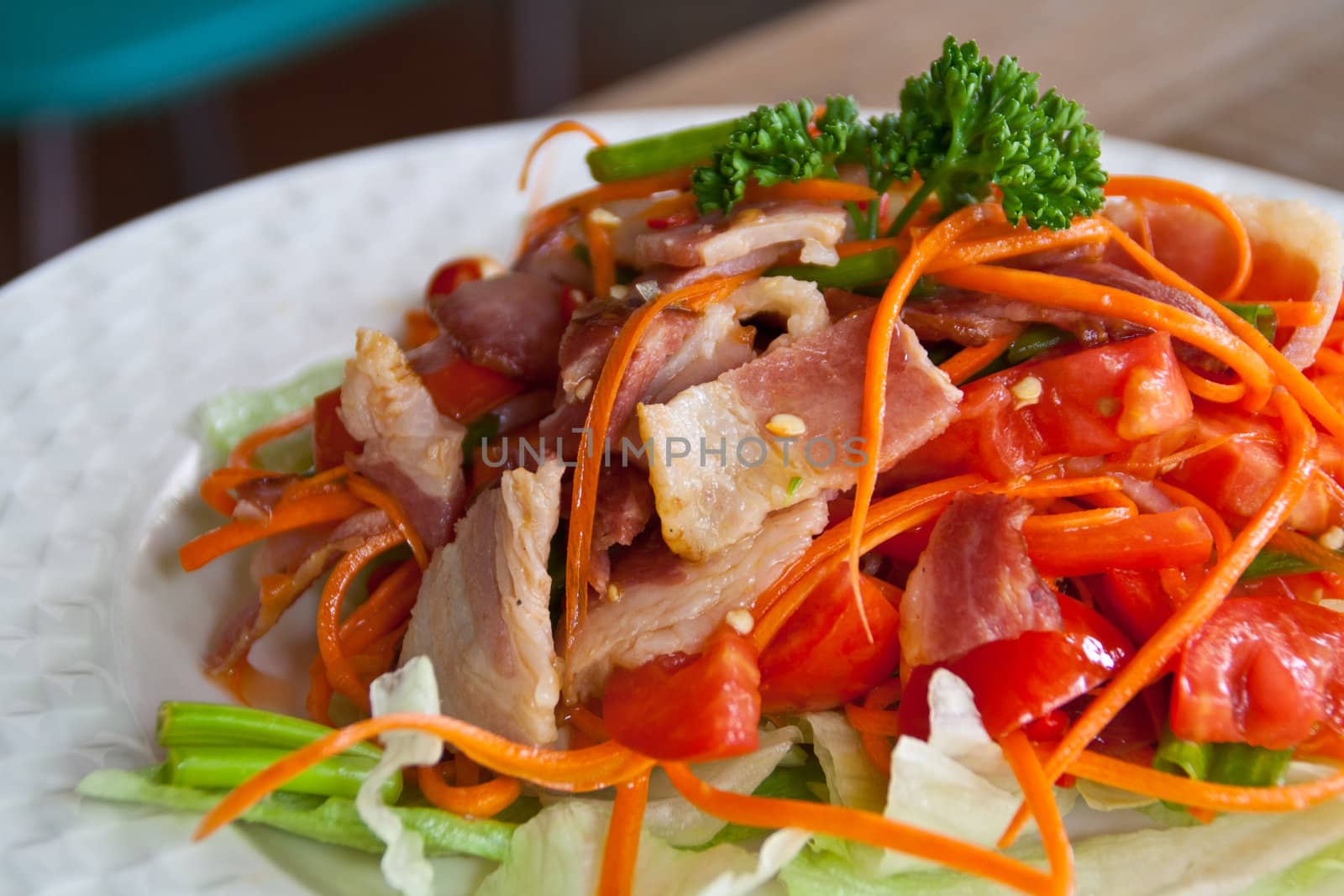 Spicy bacon salad with tomato carrot on white dish.