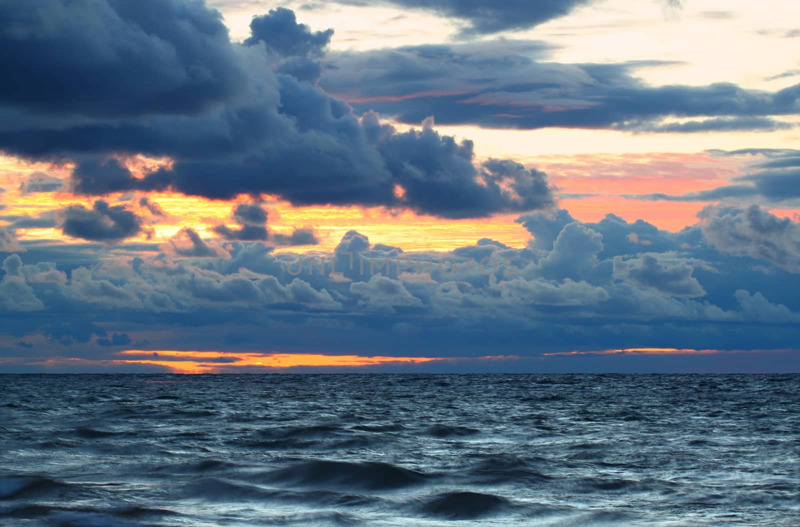 Sunset over crashing waves of Lake Superior along a northern Michigan shoreline.
