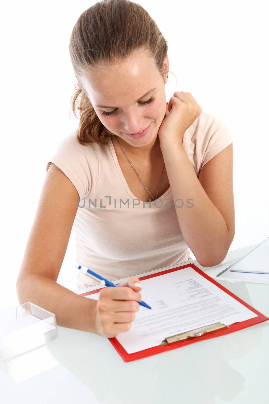 Attractive young female student smiling as she sits at a table with a clipboard reading through her exam questions 