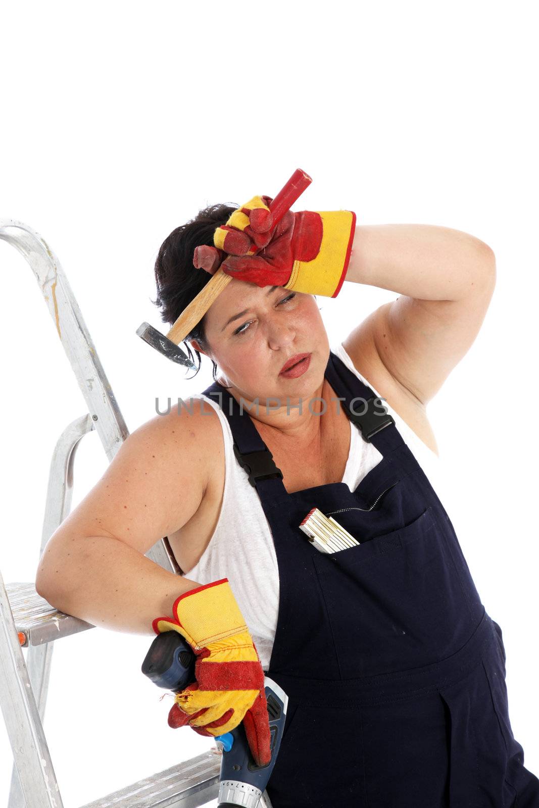 Exhausted DIY housewife or artisan wearing dungarees and safety gloves leaning against her ladder with a tired expression clutching her tools Exhausted DIY housewife or artisan leaning against her ladder with a tired expression clutching her tools 
