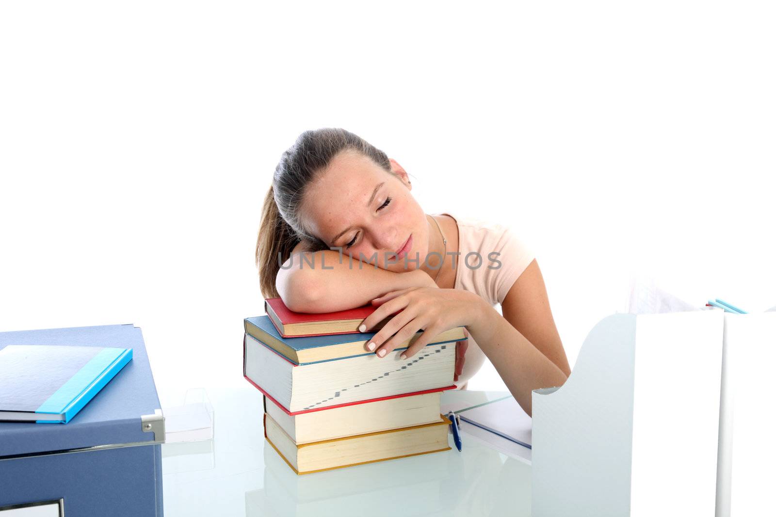 Exhausted young female college student sleeping on top of her books after a long stint of studying 