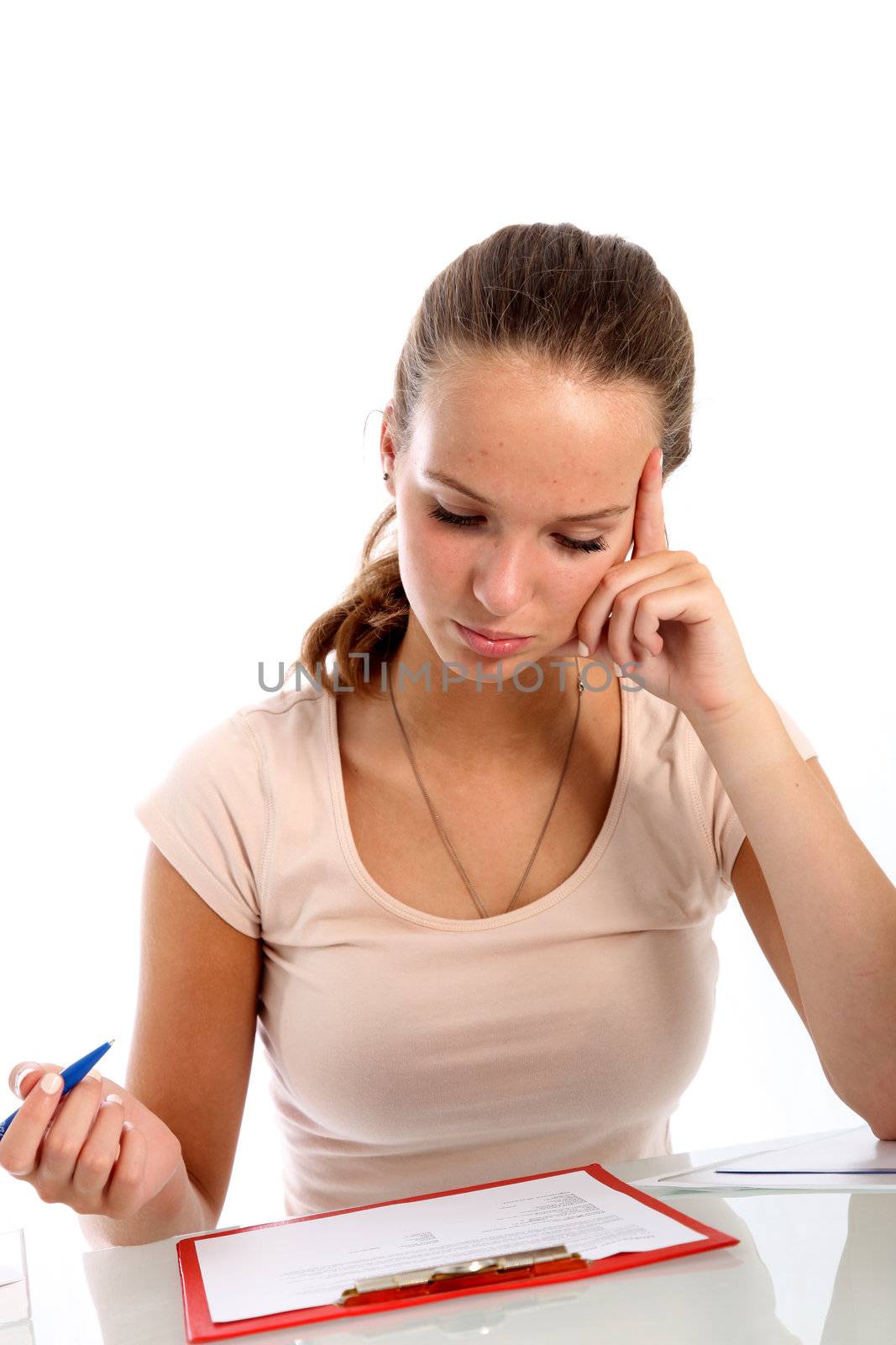 Female student seated at a table reading test questions clipped to a clipboard with a serious thoughtful expression 