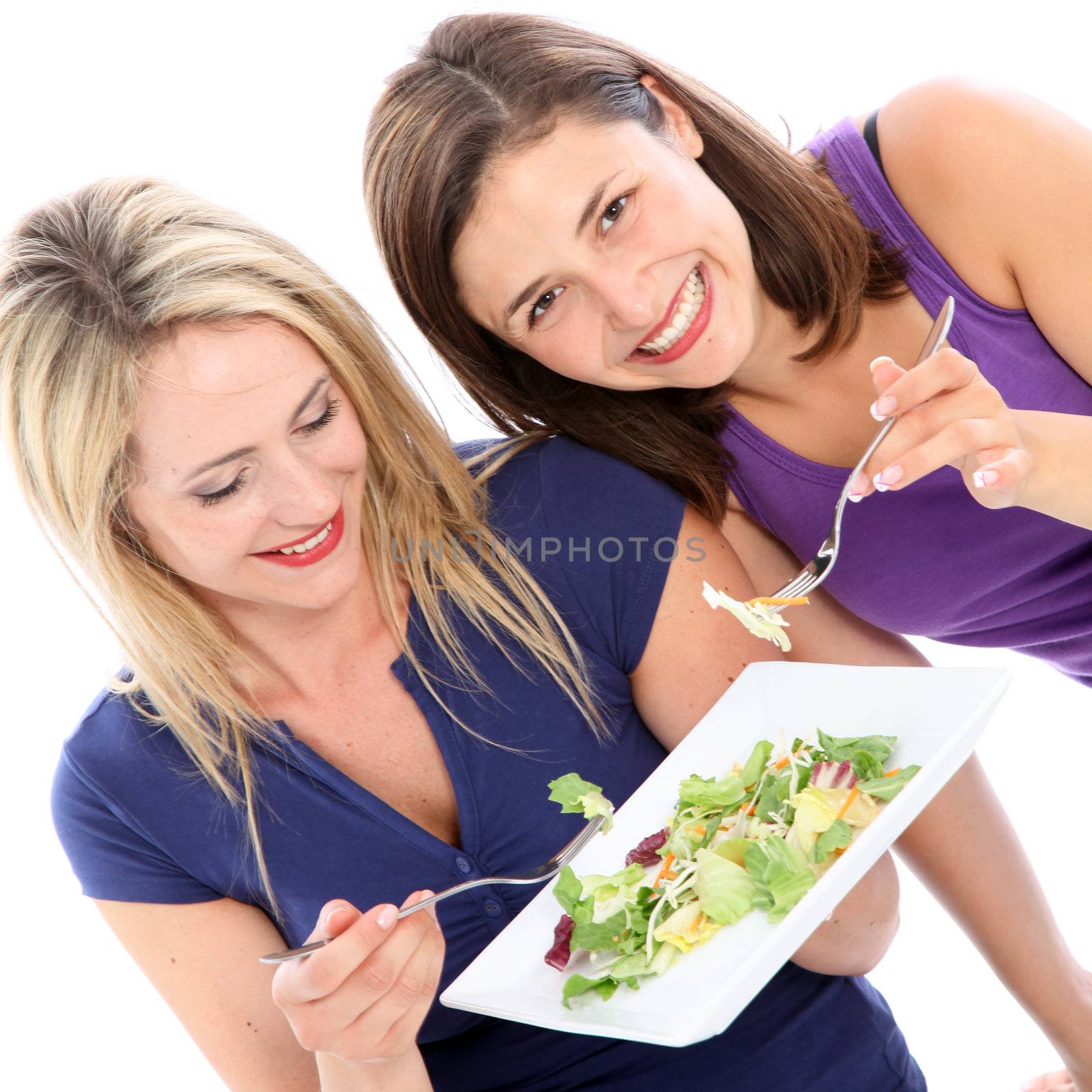 Two attractive female friends sharing a plate of healthy leafy green salad together isolated on white Two attractive female friends sharing a plate of healthy leafy green salad together isolated on whitesalad 