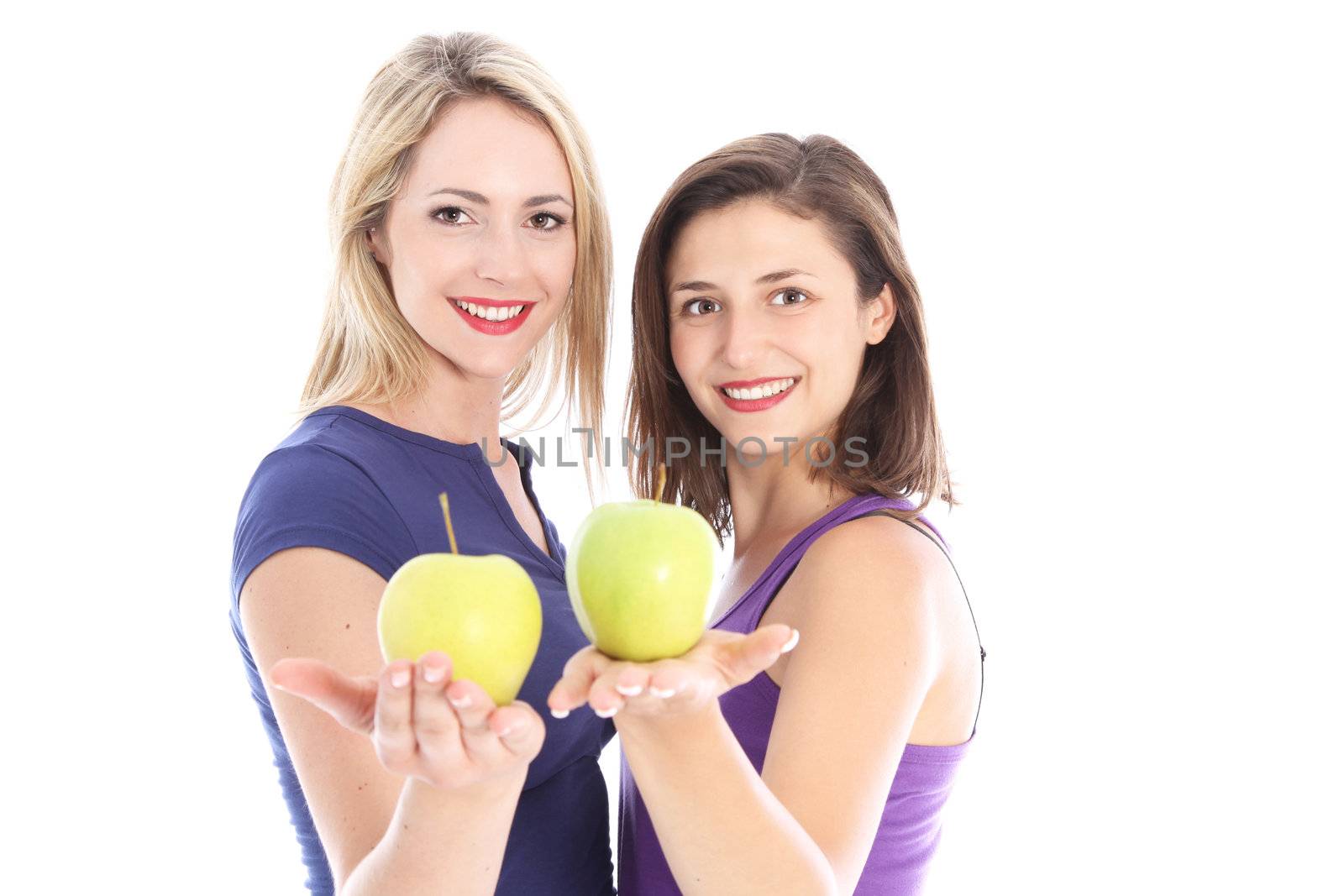 Two happy healthy women standing with their palms extended holding juicy ripe apples in a diet and fitness concept 