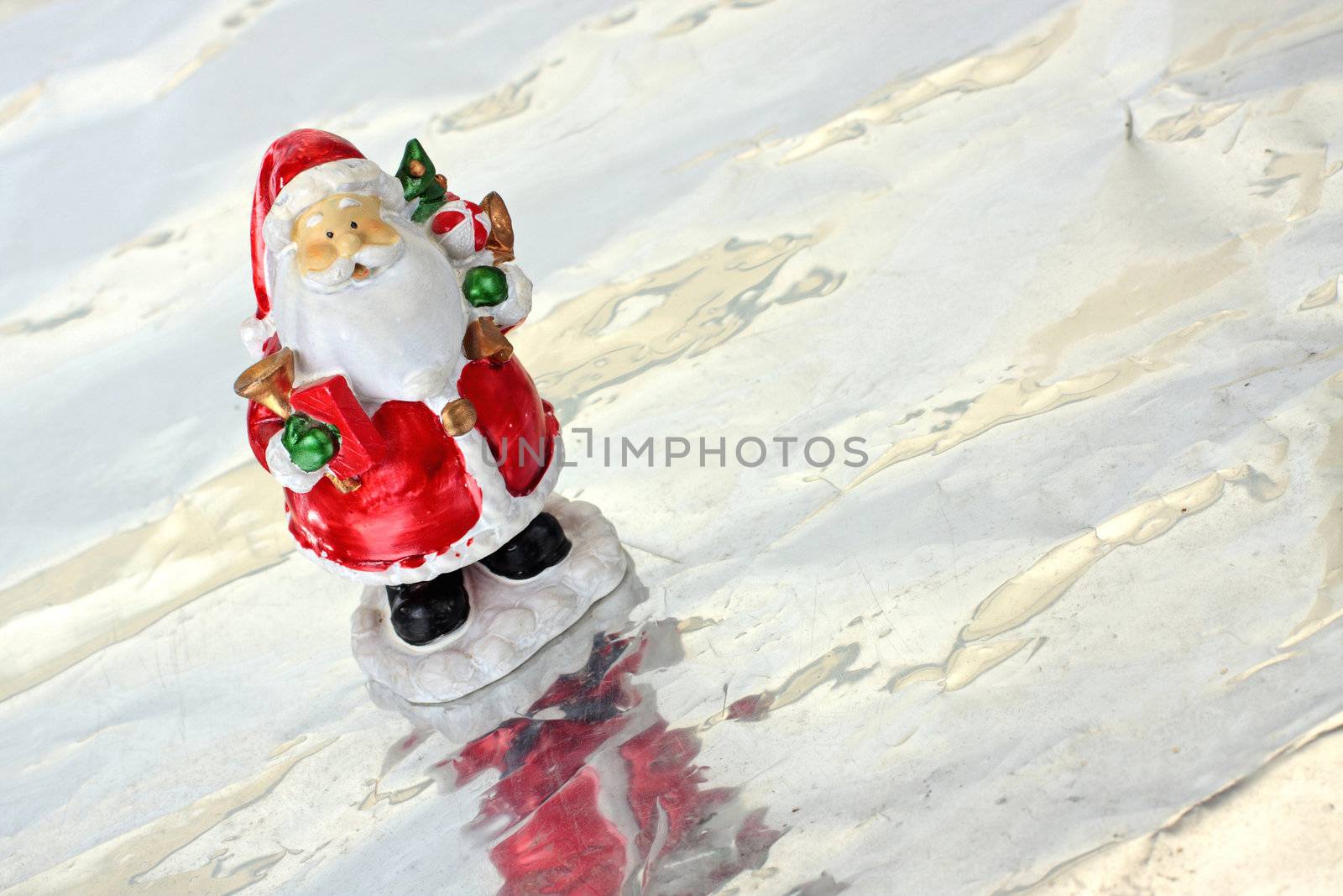 Toy Santa Claus on ice with christmas tree in hands