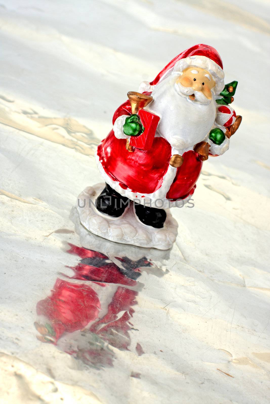 Toy Santa Claus on ice with christmas tree in hands