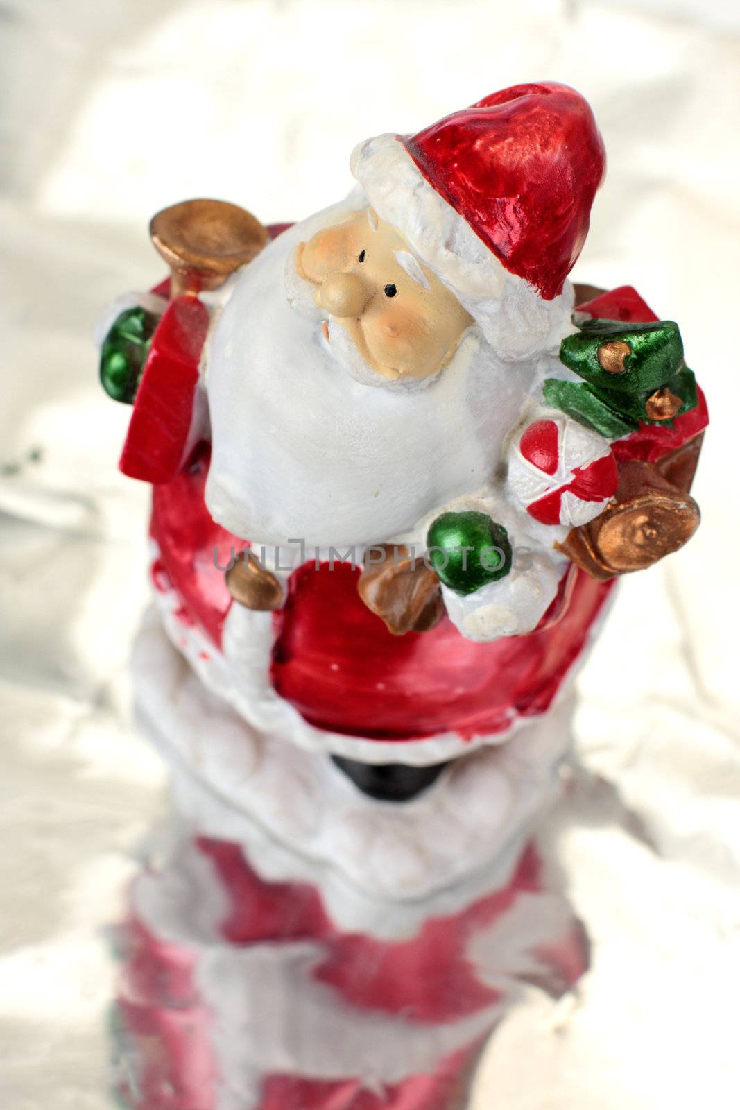 Toy Santa Claus on ice with christmas tree in hands background blurred