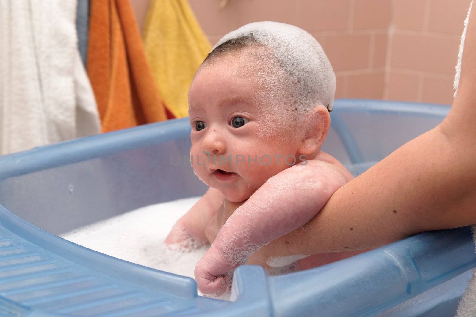Cute baby in a bathtub with foam cap on his head