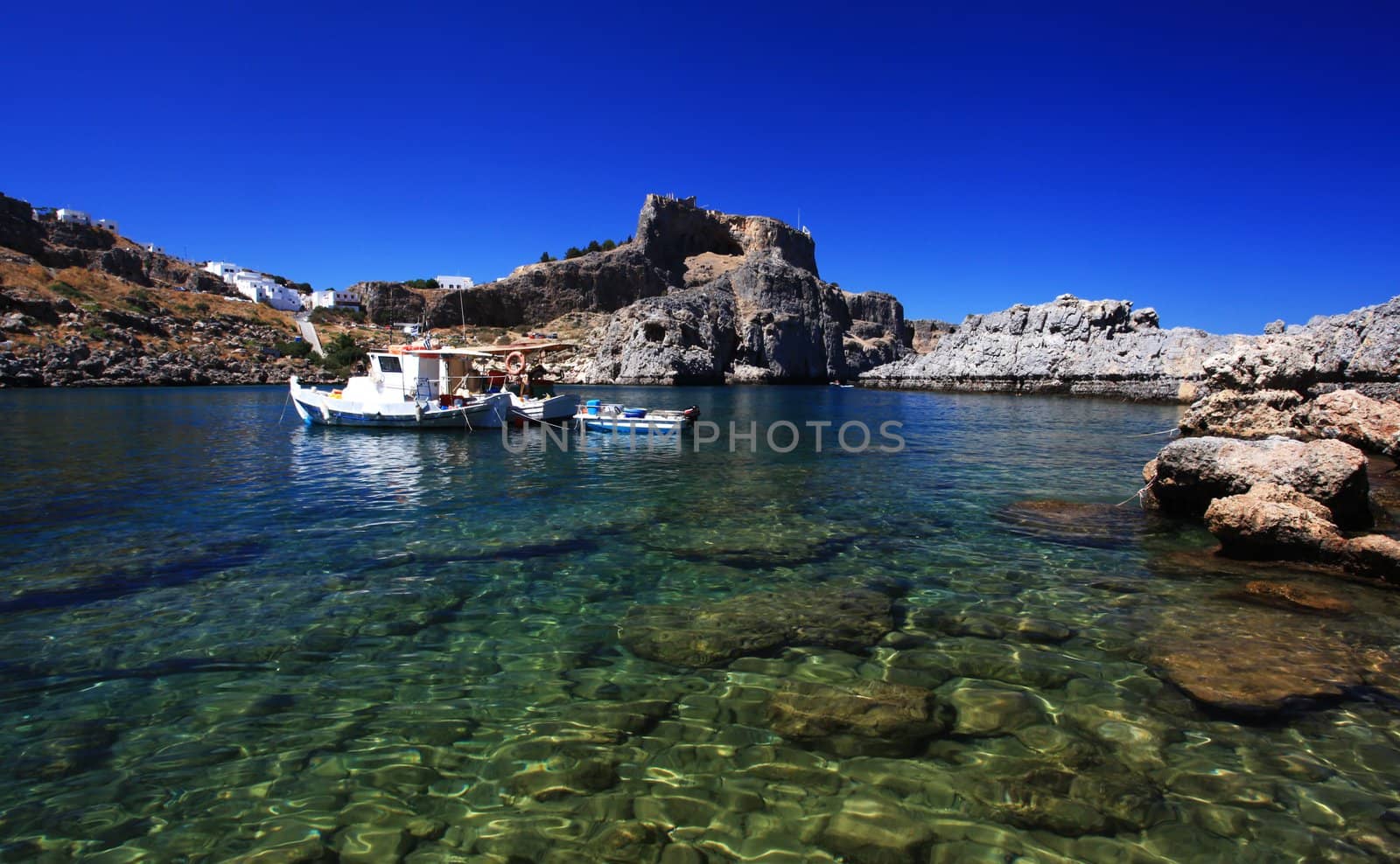 Beautiful St Pauls Bay shadowed by the temple and castle ruins at Lindos 