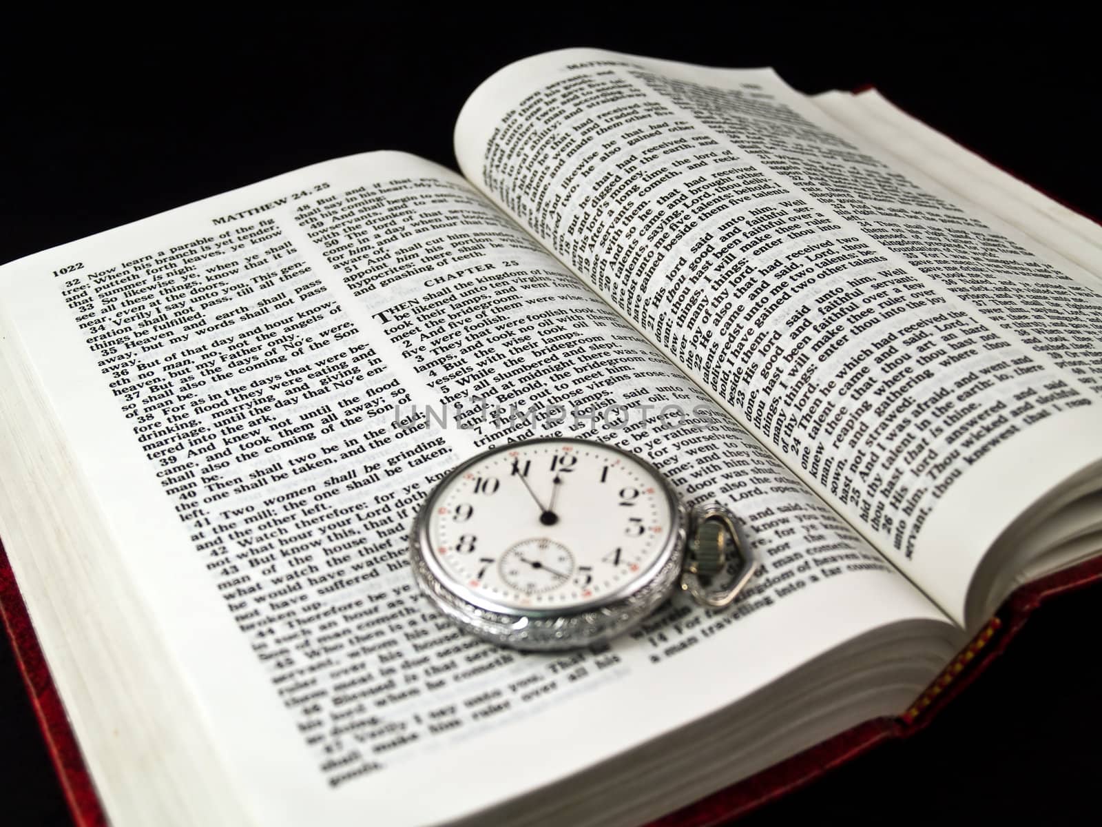 The Bible opened to Matthew 24: 36 with a Pocketwatch - warm color tone  "No man knows the day or hour"