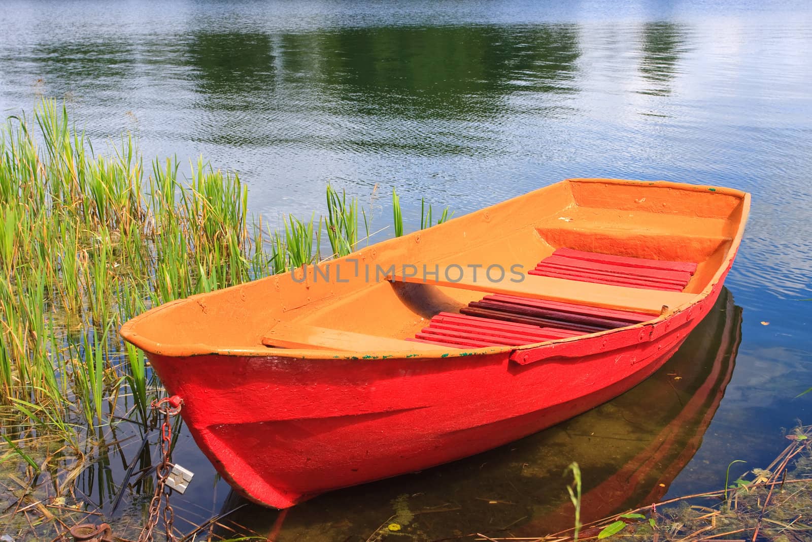 Red rowing boat on lake by Verdateo