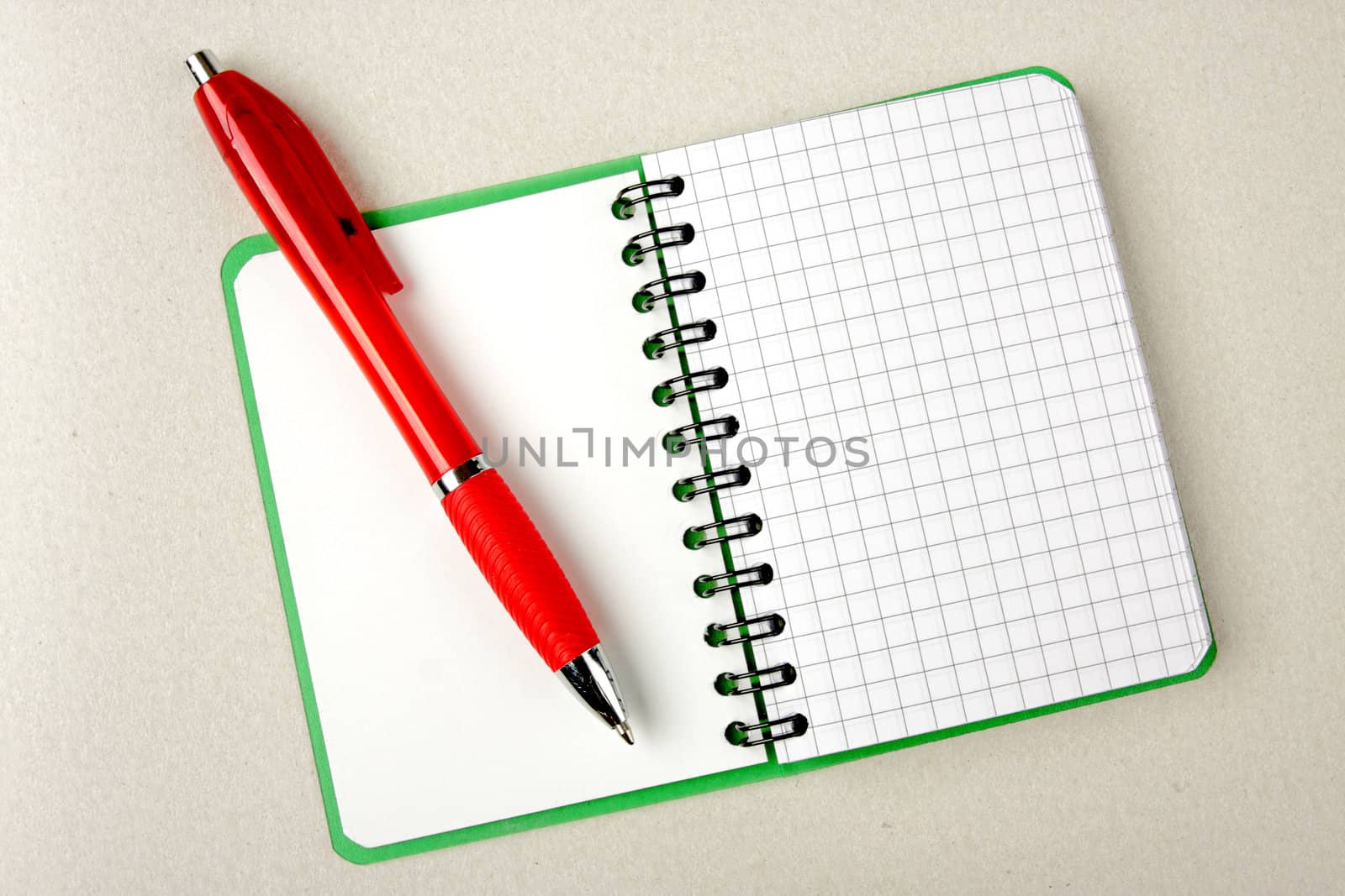 Opened notebook squared pagewith red pen over it on grey backgro by Verdateo
