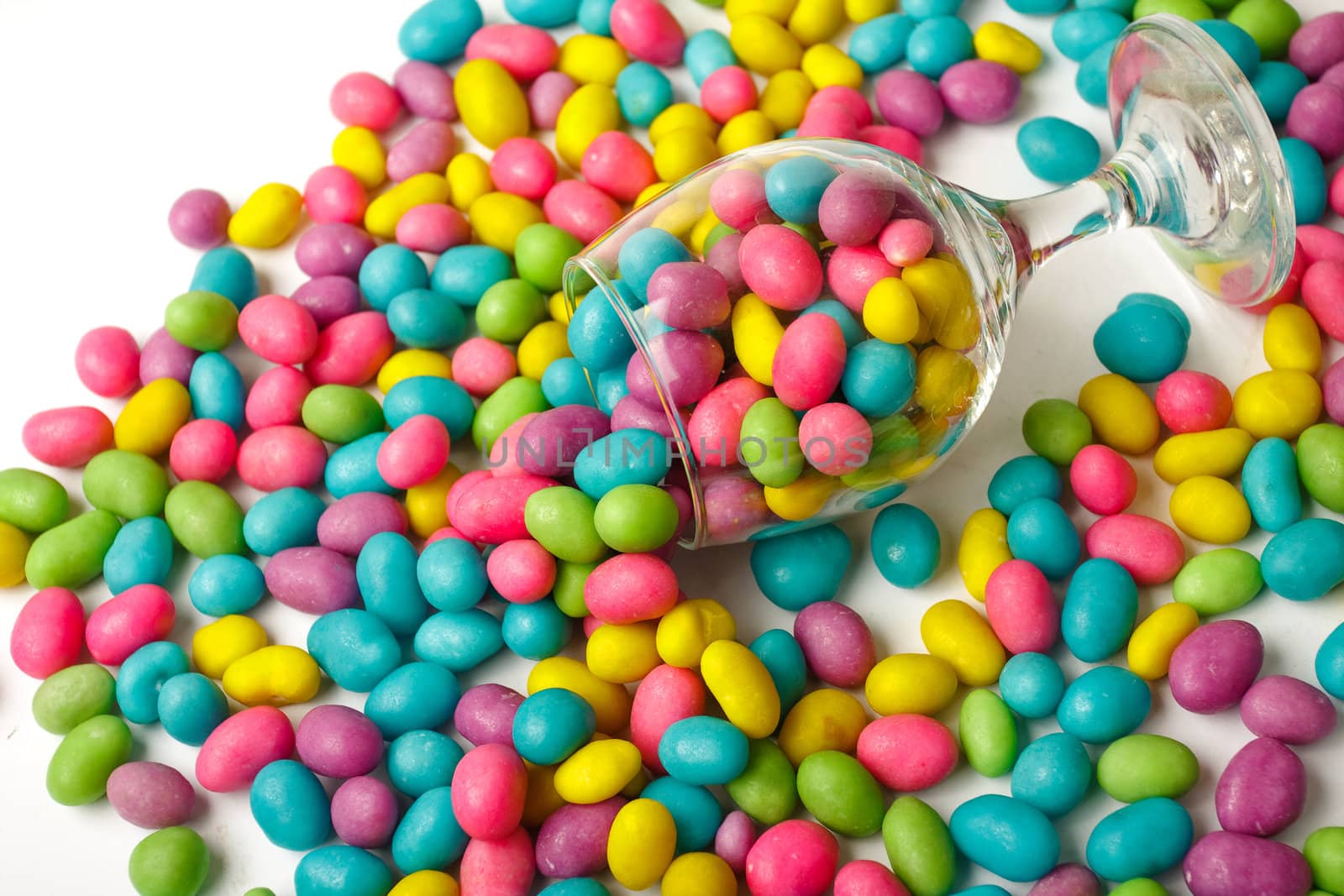 Color candie beans in glass on white background