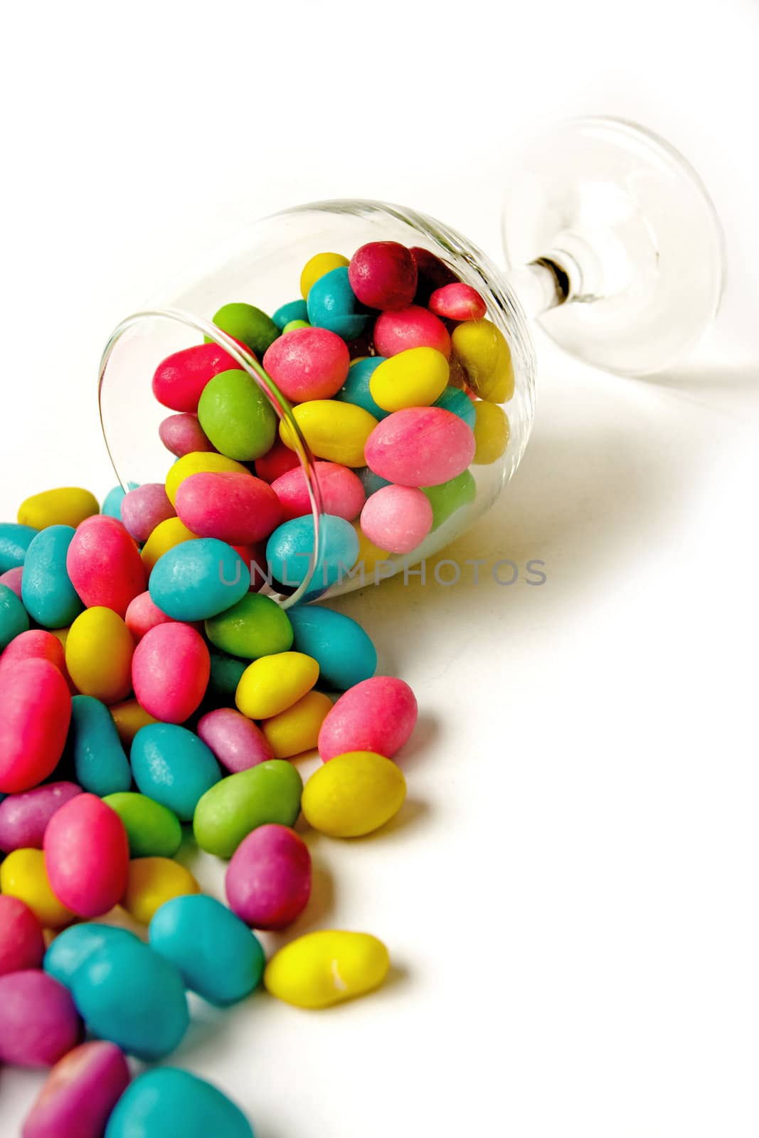 Color candie beans in glass on white background
