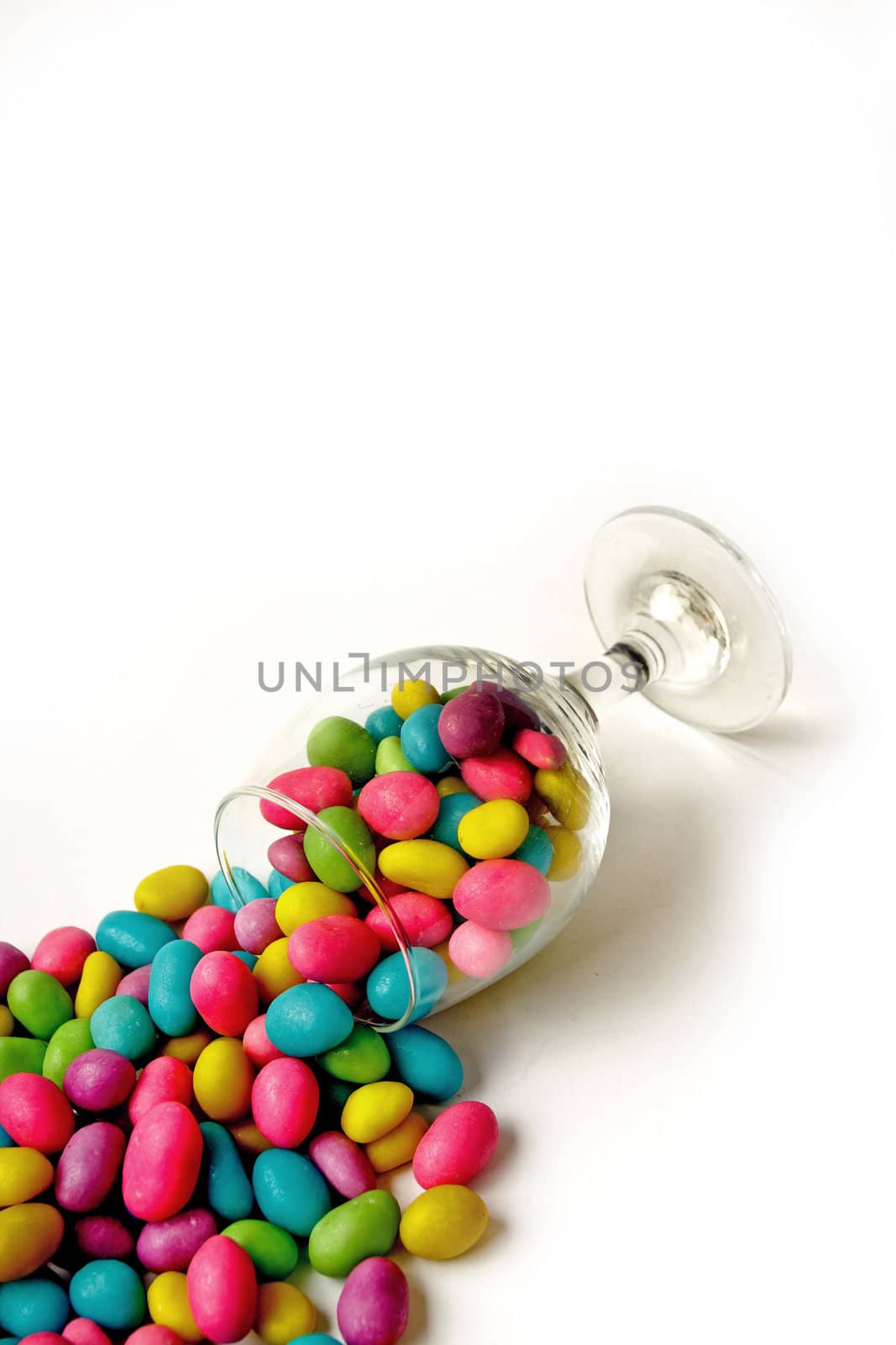Color candie beans in glass on white background by Verdateo