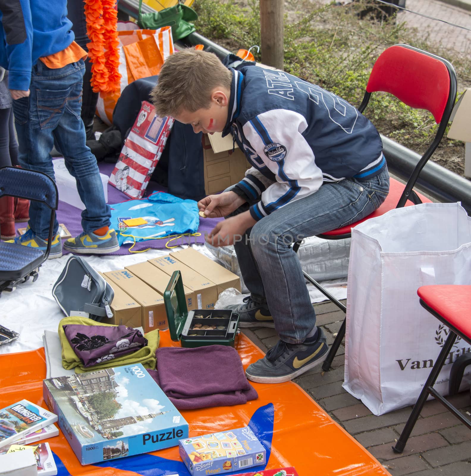 MELISSANT,HOLLAND - APRIL 30 unidentified boy countinh his money earned from sale on the market on queensday on April 30, 2013 in Melissant, The Netherlands,this market is once a year with queensday