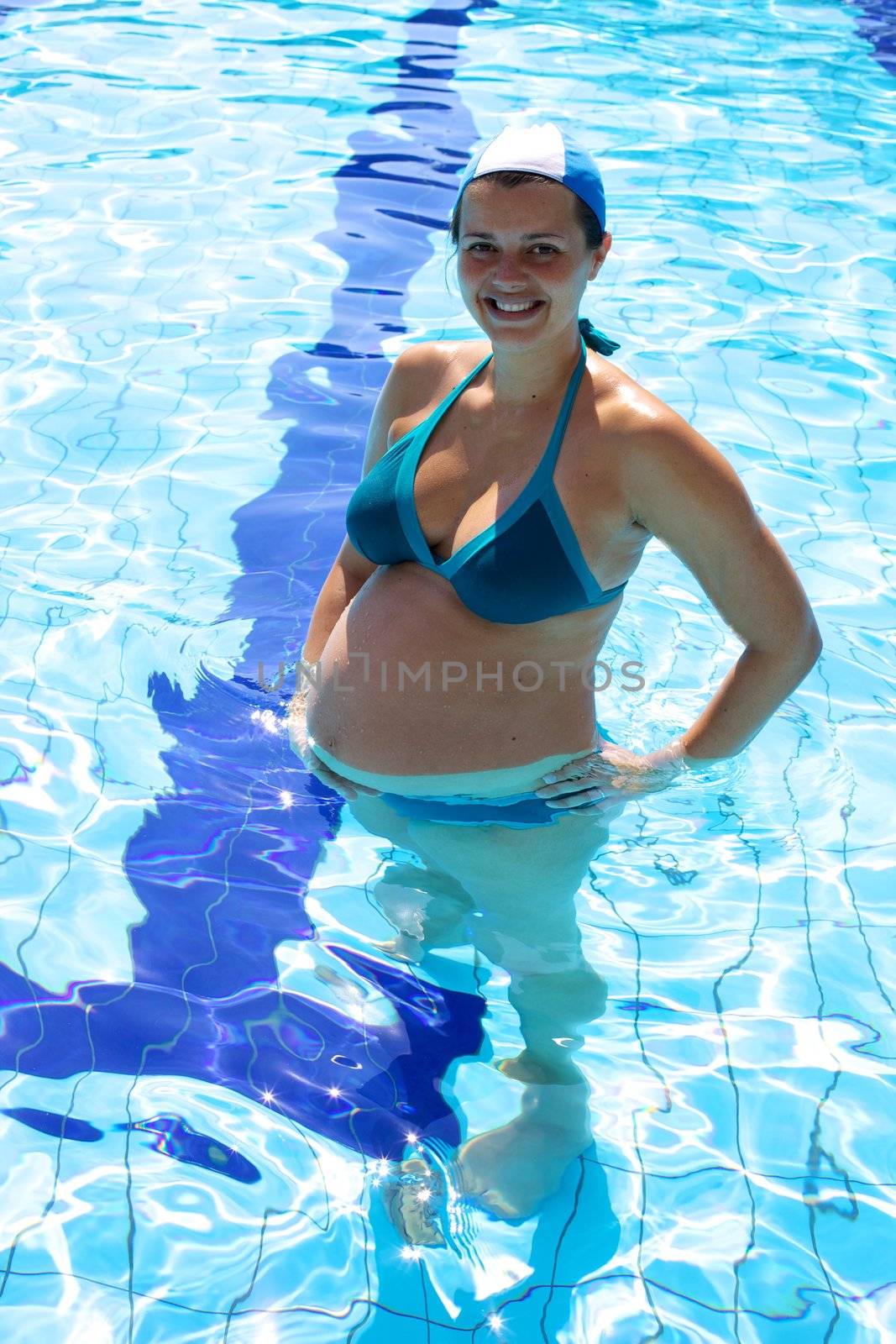 Smiling happy pregnant woman in swimming pool by fmarsicano