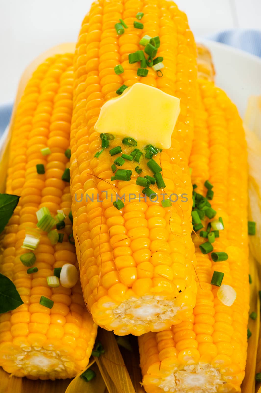 Cooked corn with butter and chives on white background