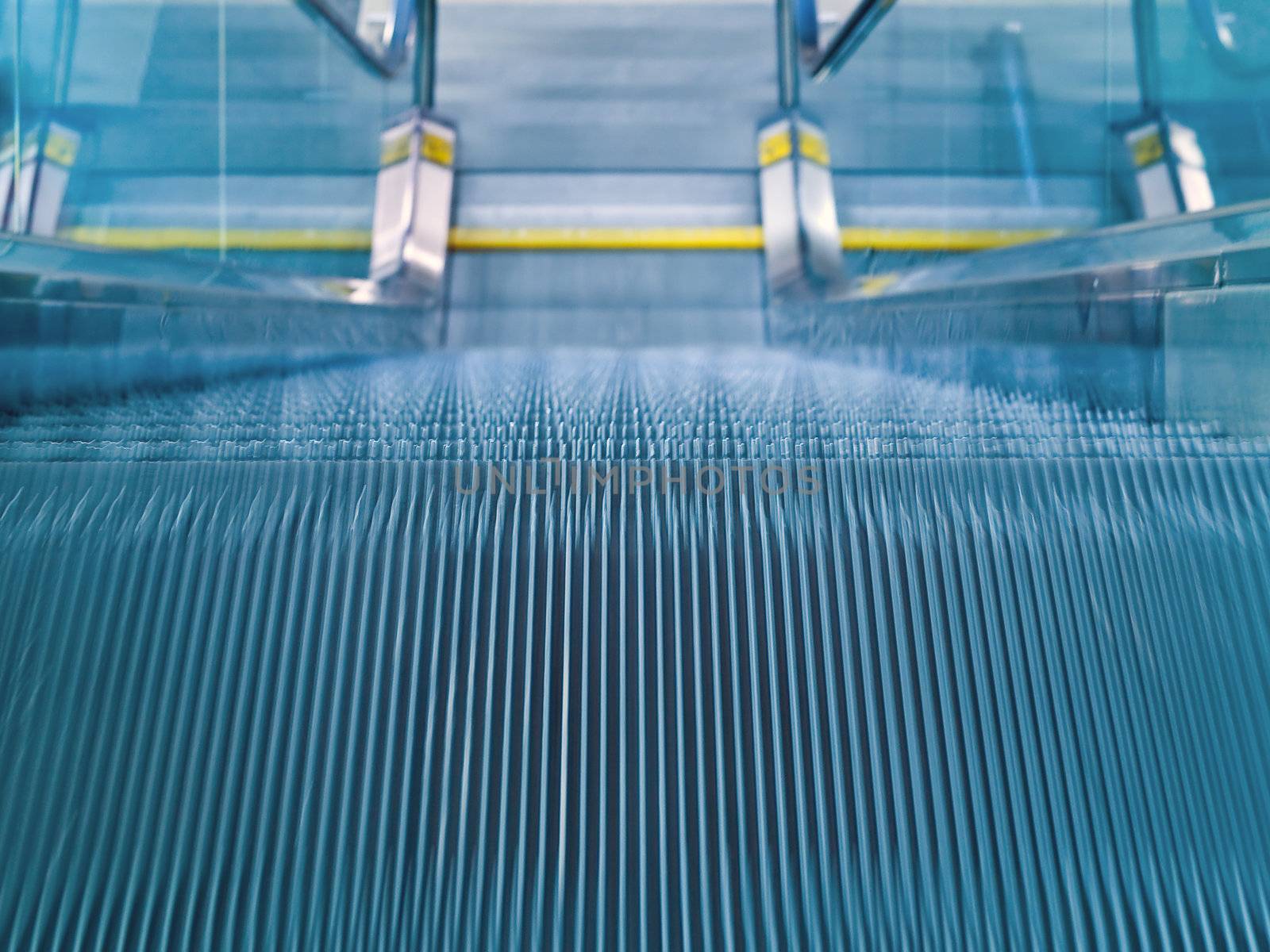 An airport escalator from the top landing showing motion blur