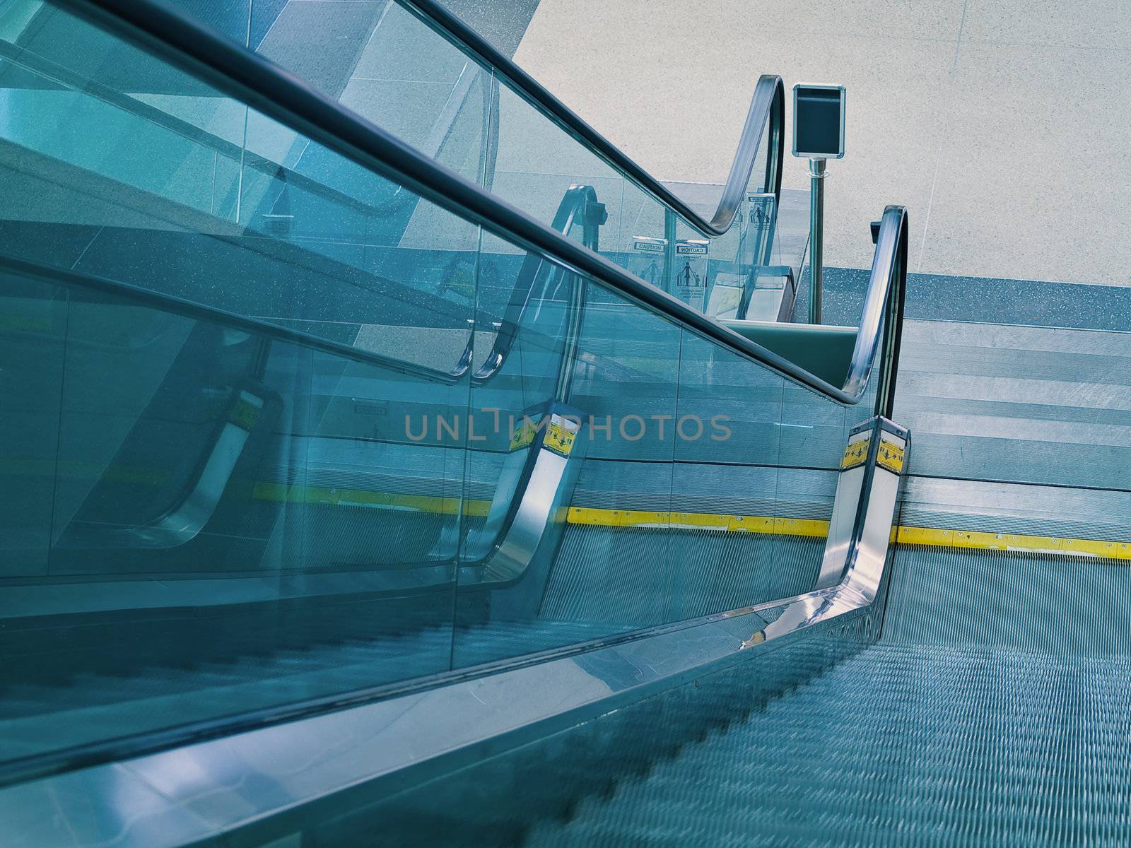 An airport escalator from the top landing showing motion blur