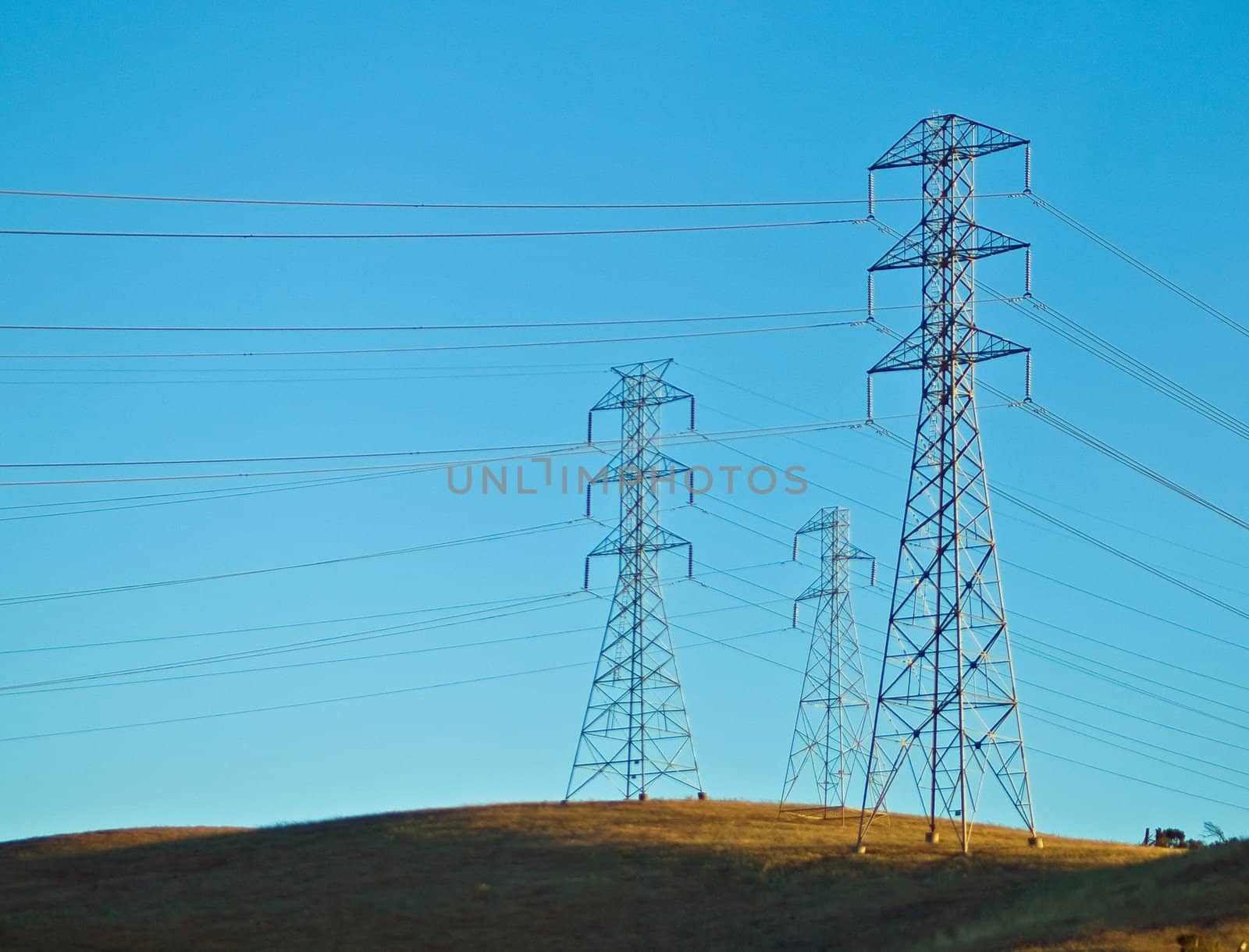 Electrical Powerlines on a Hill before a Blue Sky by Frankljunior
