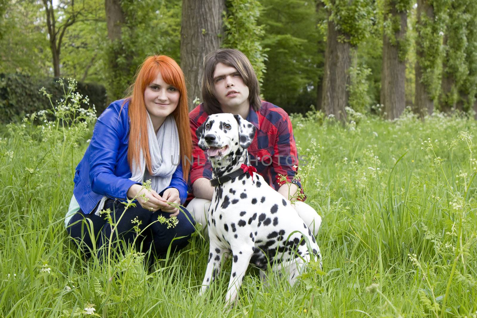 Young couple with a dog on the grass in the park