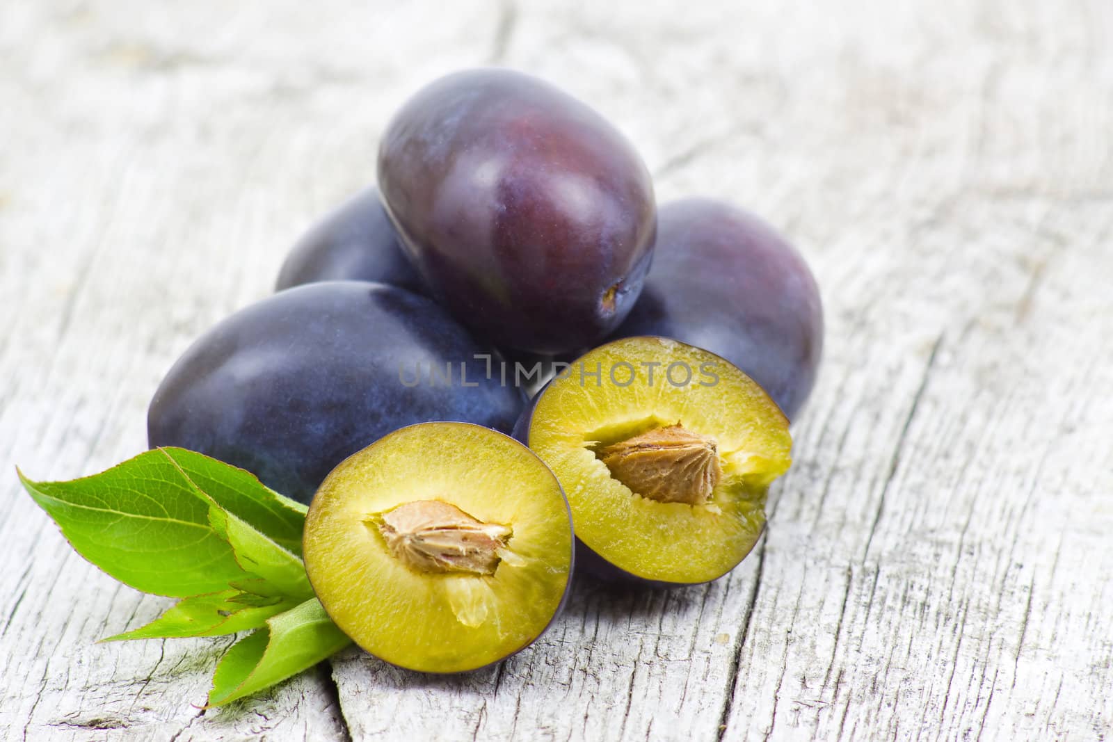 Fresh plums on old wooden background